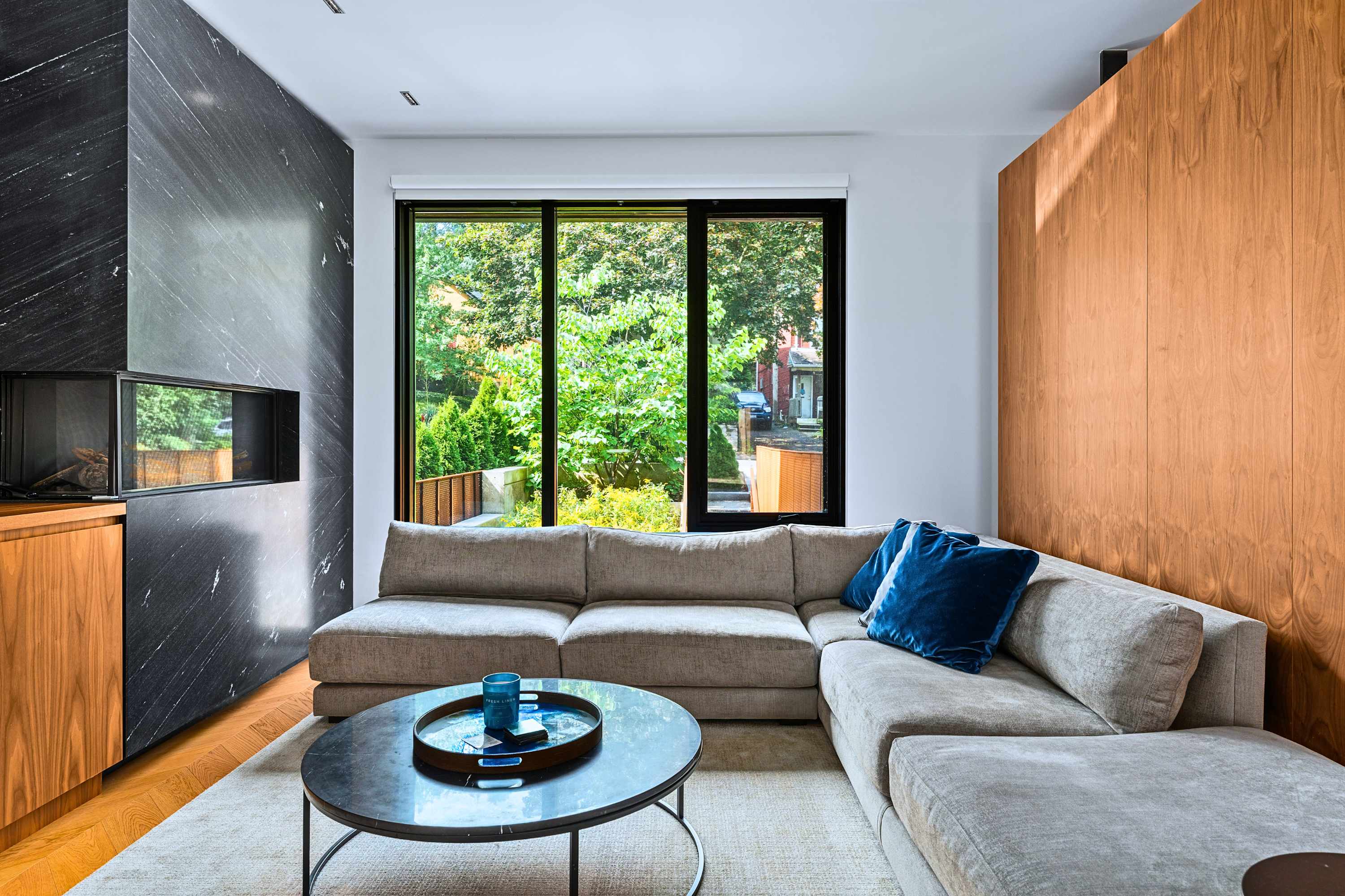Feature fireplace wall framed by floor-to-ceiling windows and wood paneling.