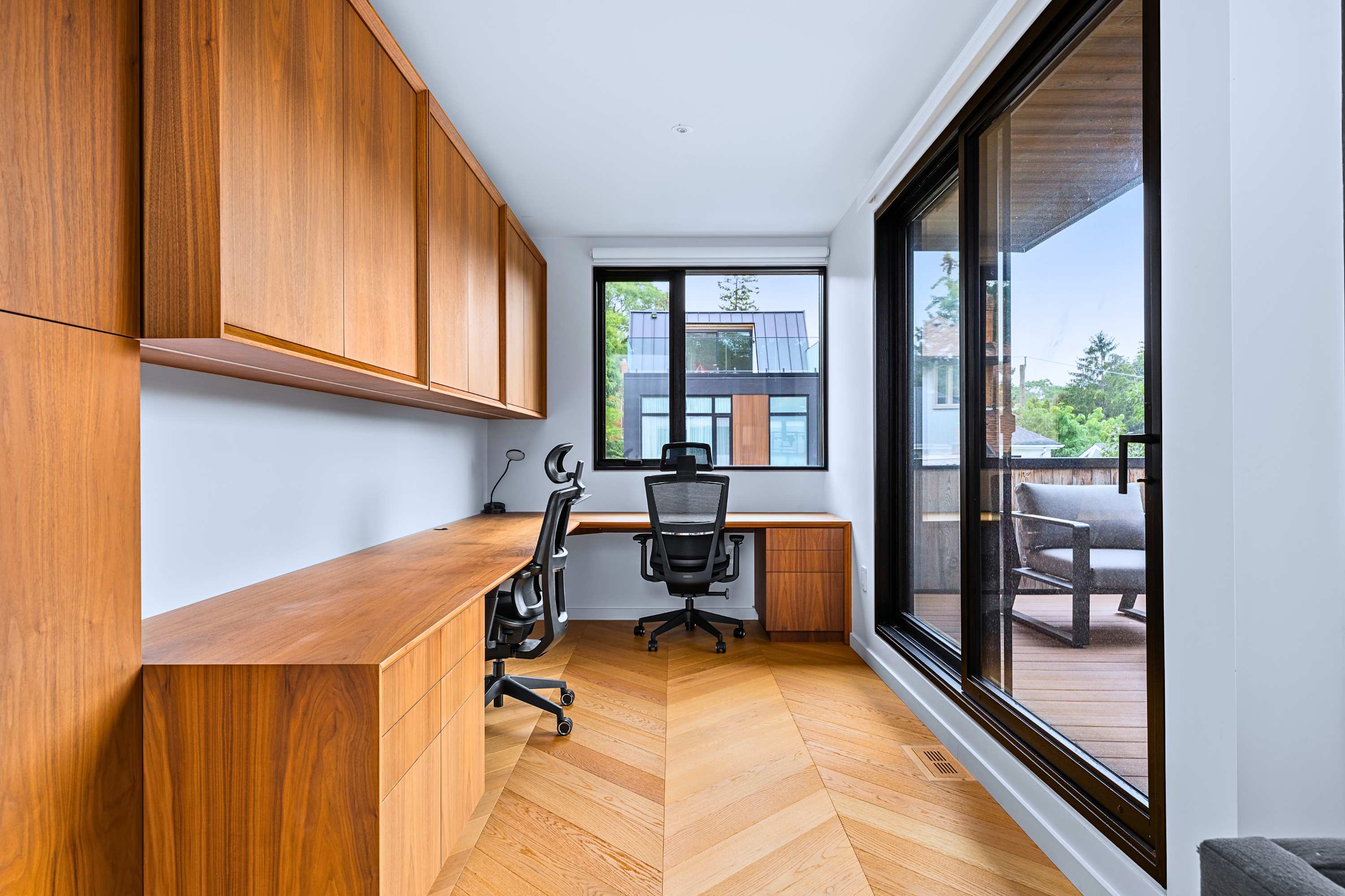 Executive home office workstation featuring a wide desk and ergonomic chairs.