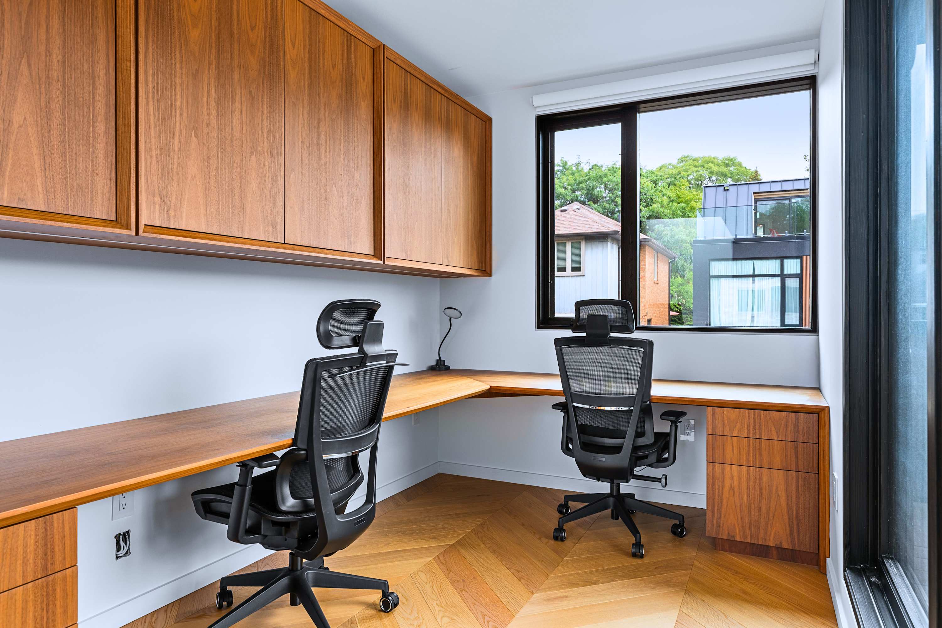 Dual-station home workspace with natural window light and upper cabinets.