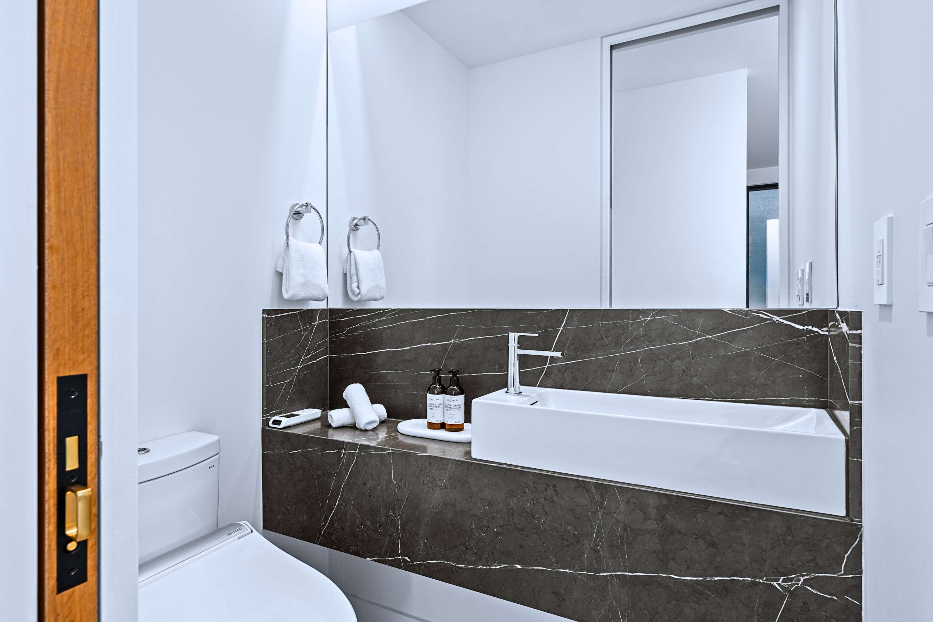 Sleek powder room with floating vanity and dark tile accents.