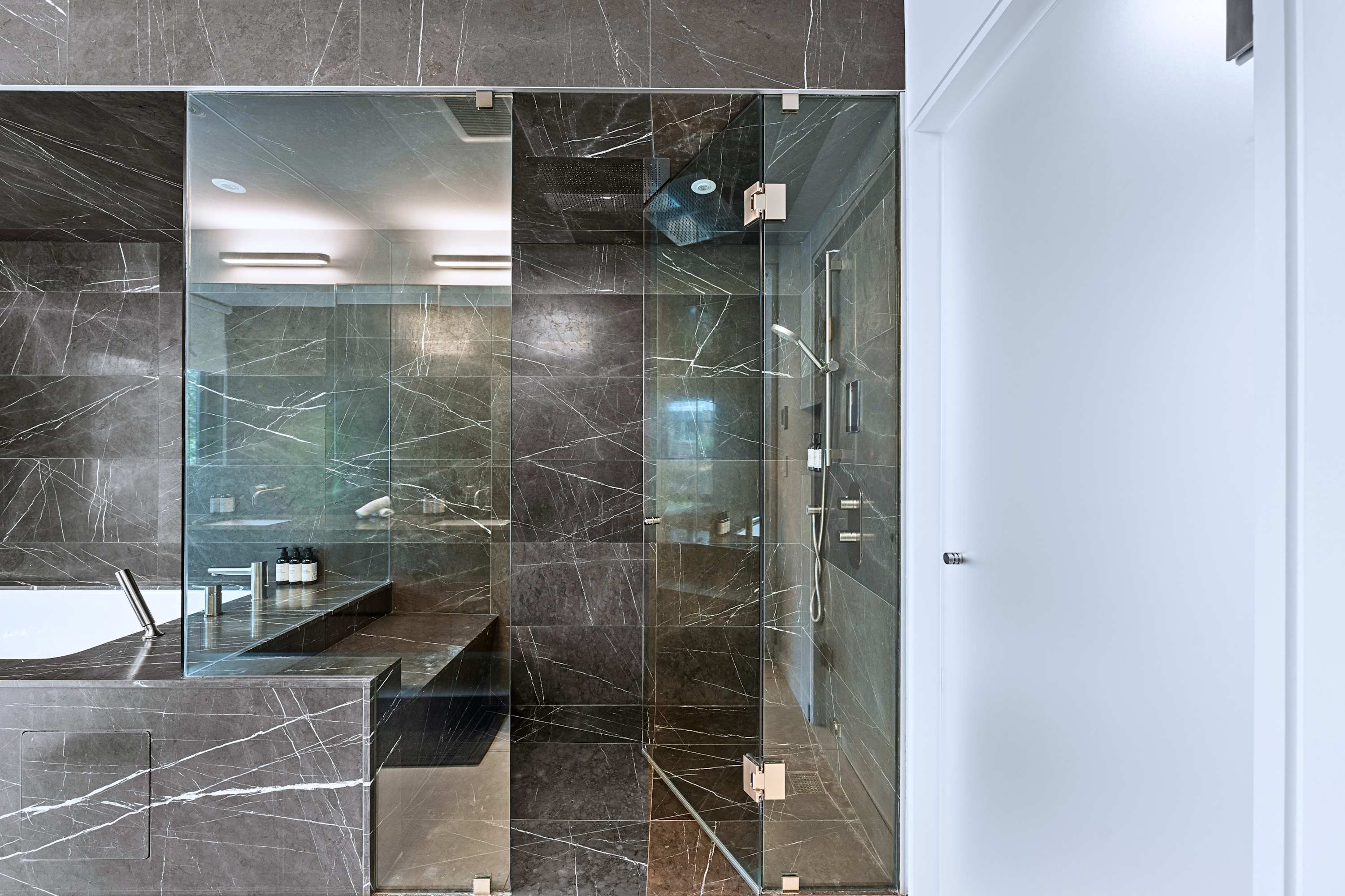 Walk-in glass shower enclosure finished in floor-to-ceiling slate tile.