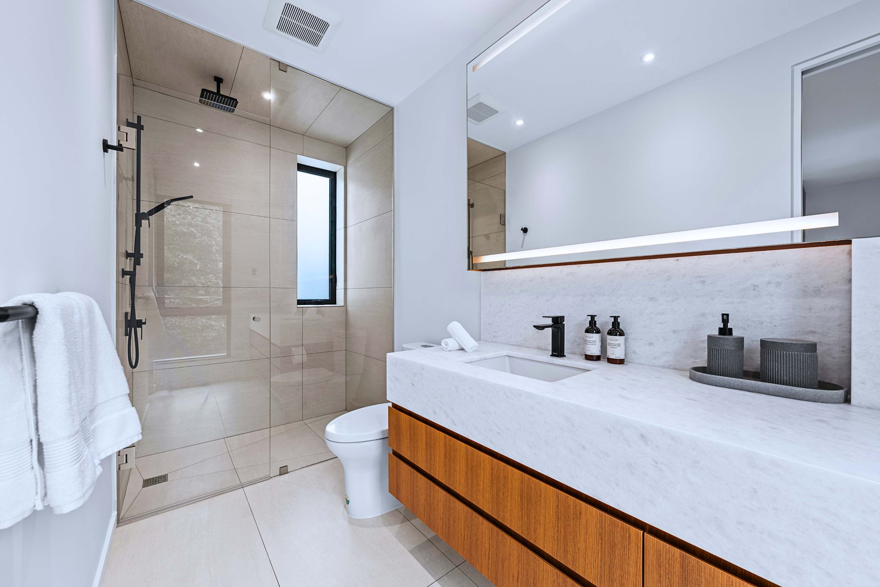 Primary en-suite featuring floating double vanity and backlit LED mirror.