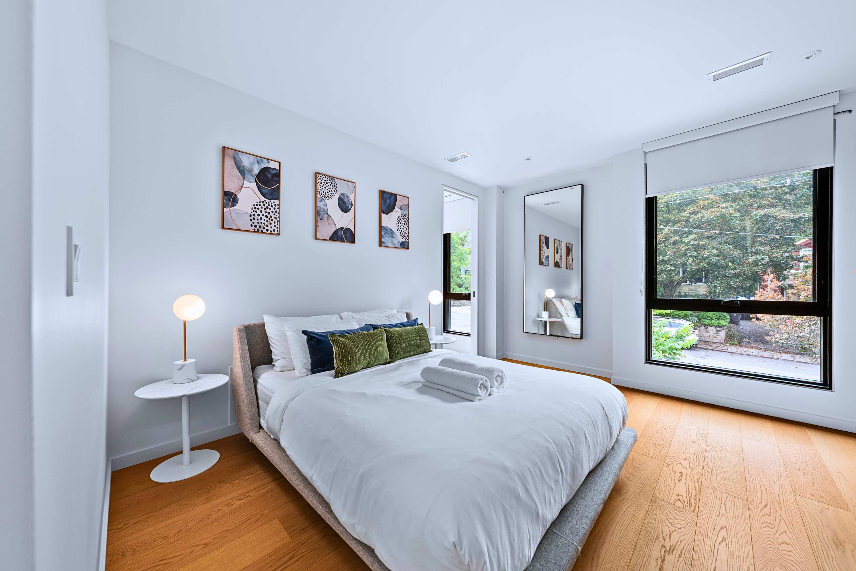 Sunlit queen bedroom with hotel-grade linens and wall art decor.