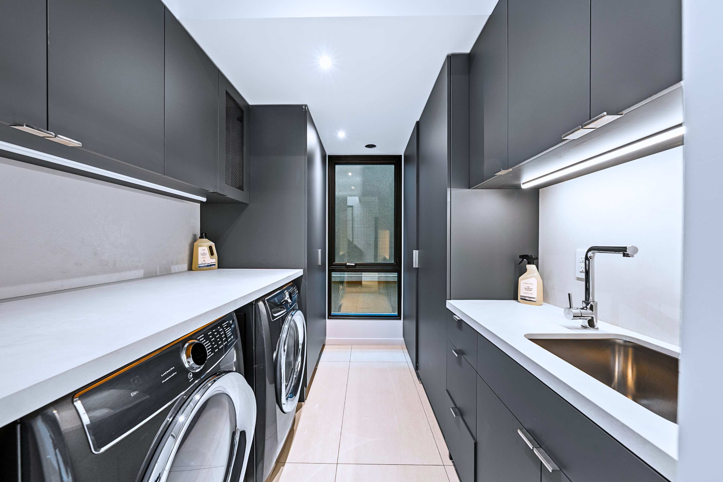 Dedicated laundry room with front-load machines, sink, and storage.