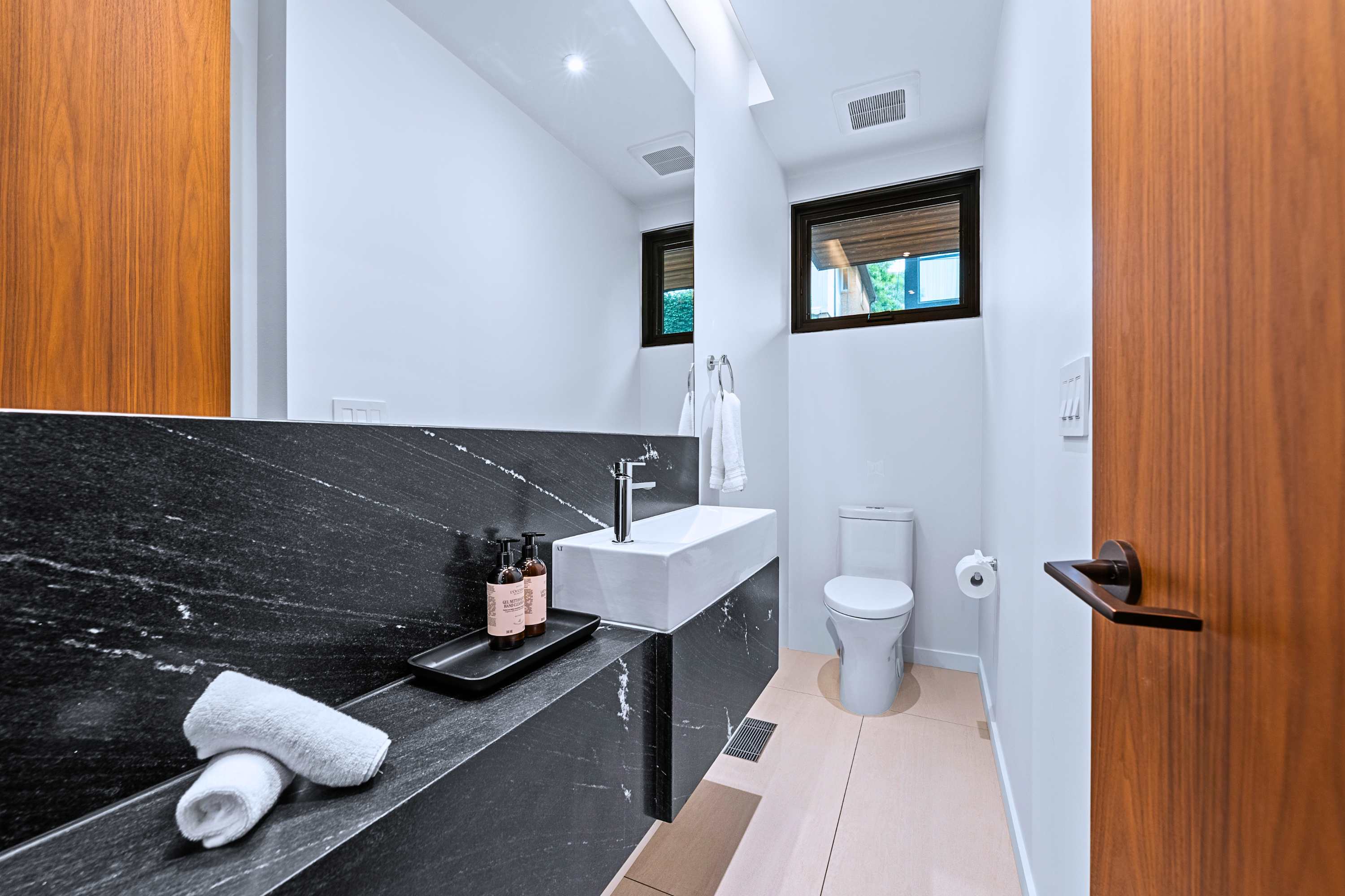 Modern powder room featuring black fixtures and dark tile vanity.