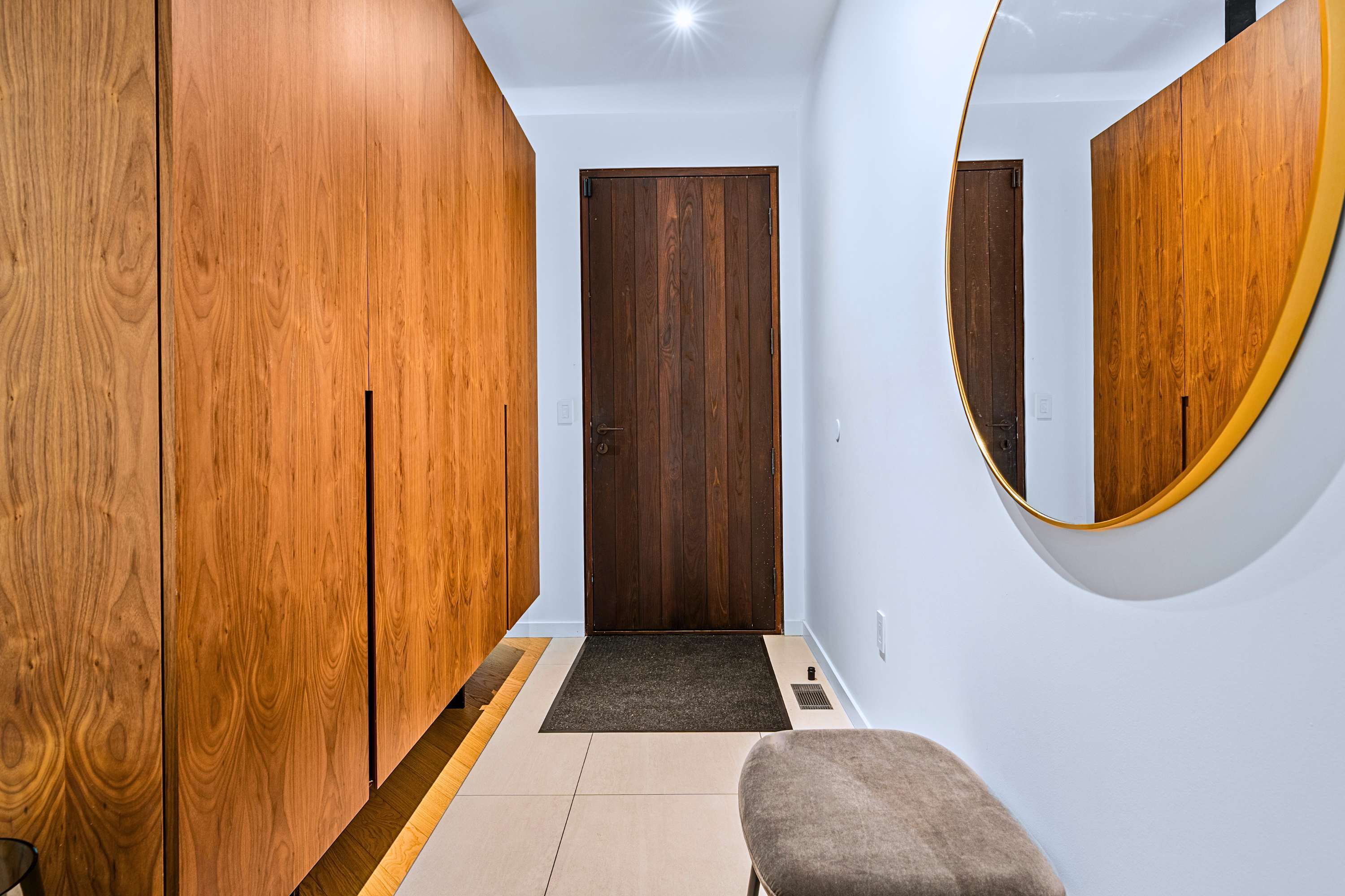 Foyer with a welcoming oversized circular mirror and soft light.