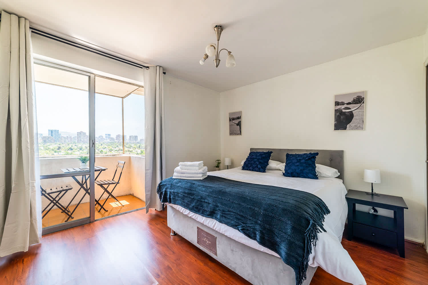 Comfortable bedroom with navy accents, fresh towels, and a private balcony offering city and green-space views.