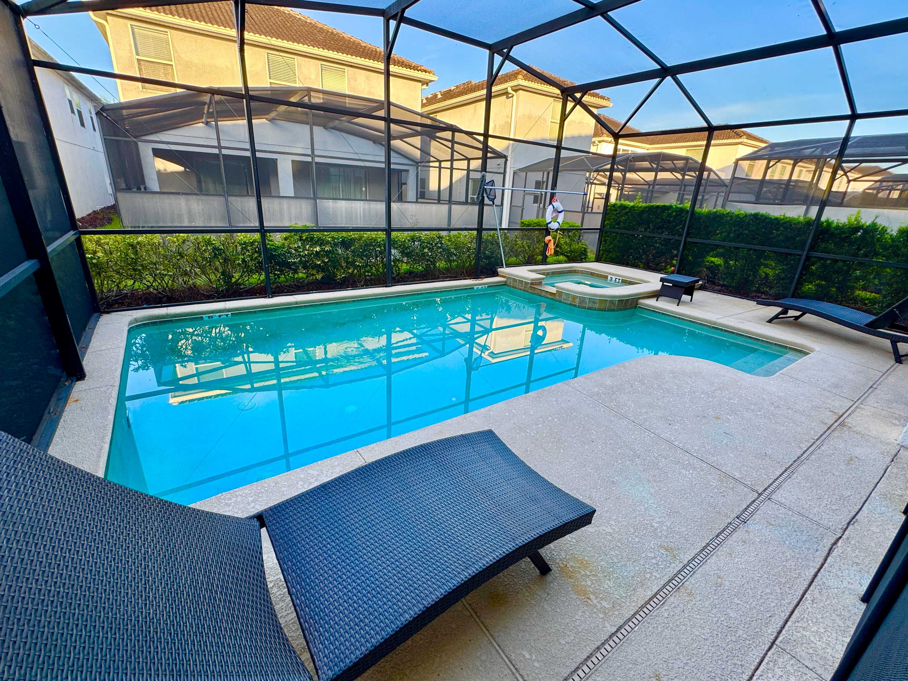 Screened private pool with a raised spa, turquoise water, and chaise lounges beside the spacious villa patio.