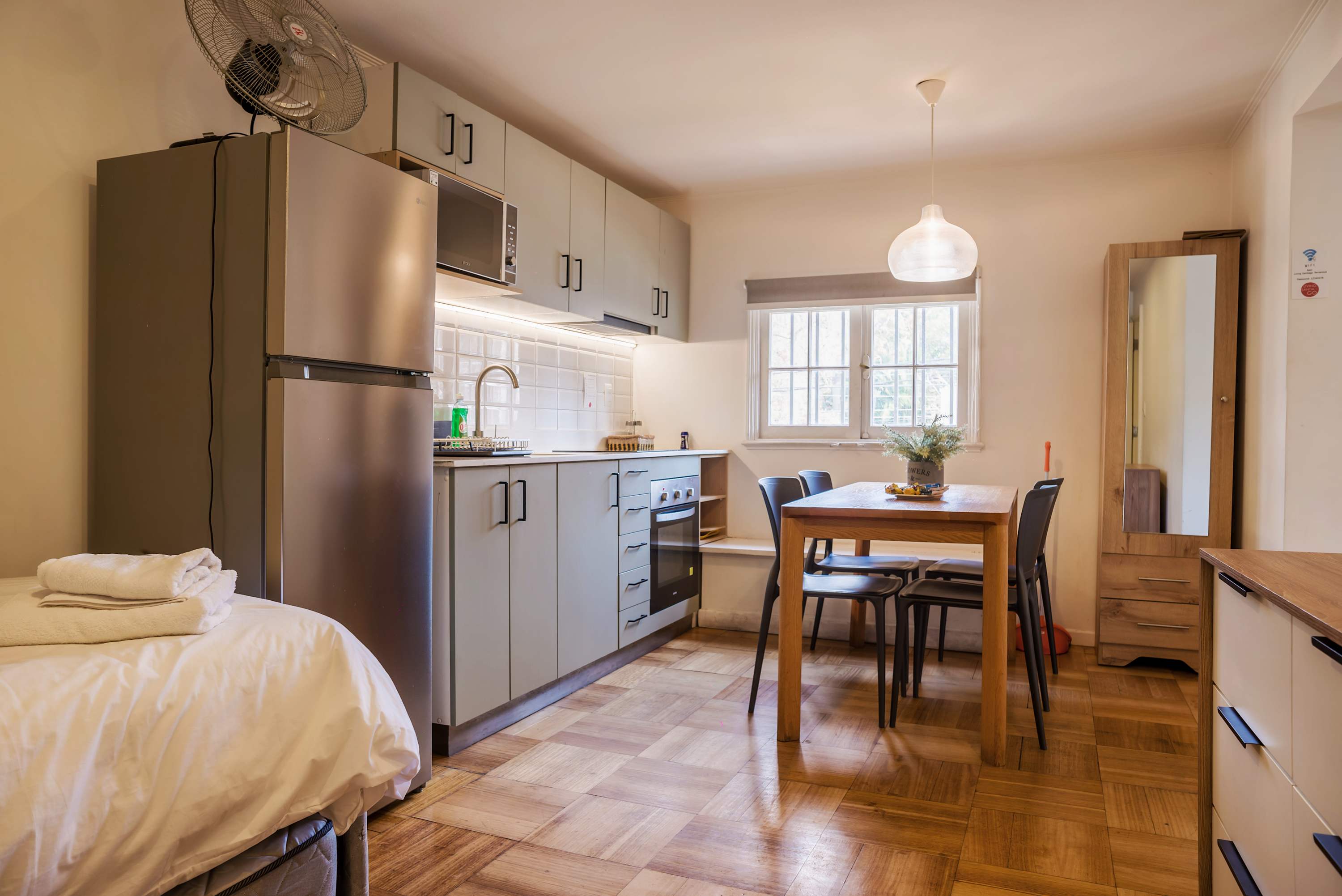 Private kitchen and dining area with seating for five, full-size appliances, and a bright window overlooking greenery.
