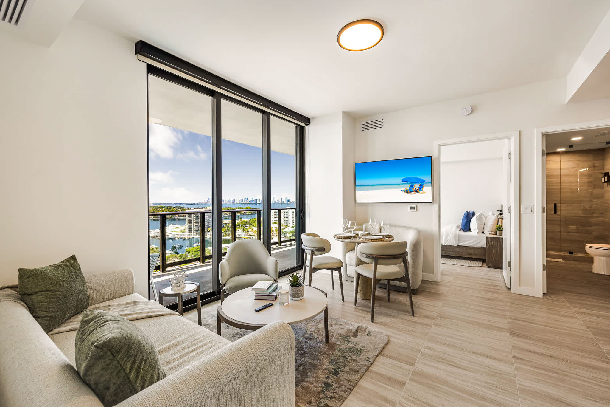 Bright living room with floor-to-ceiling windows, a private balcony, and sweeping views of the marina, waterways, and city skyline.
