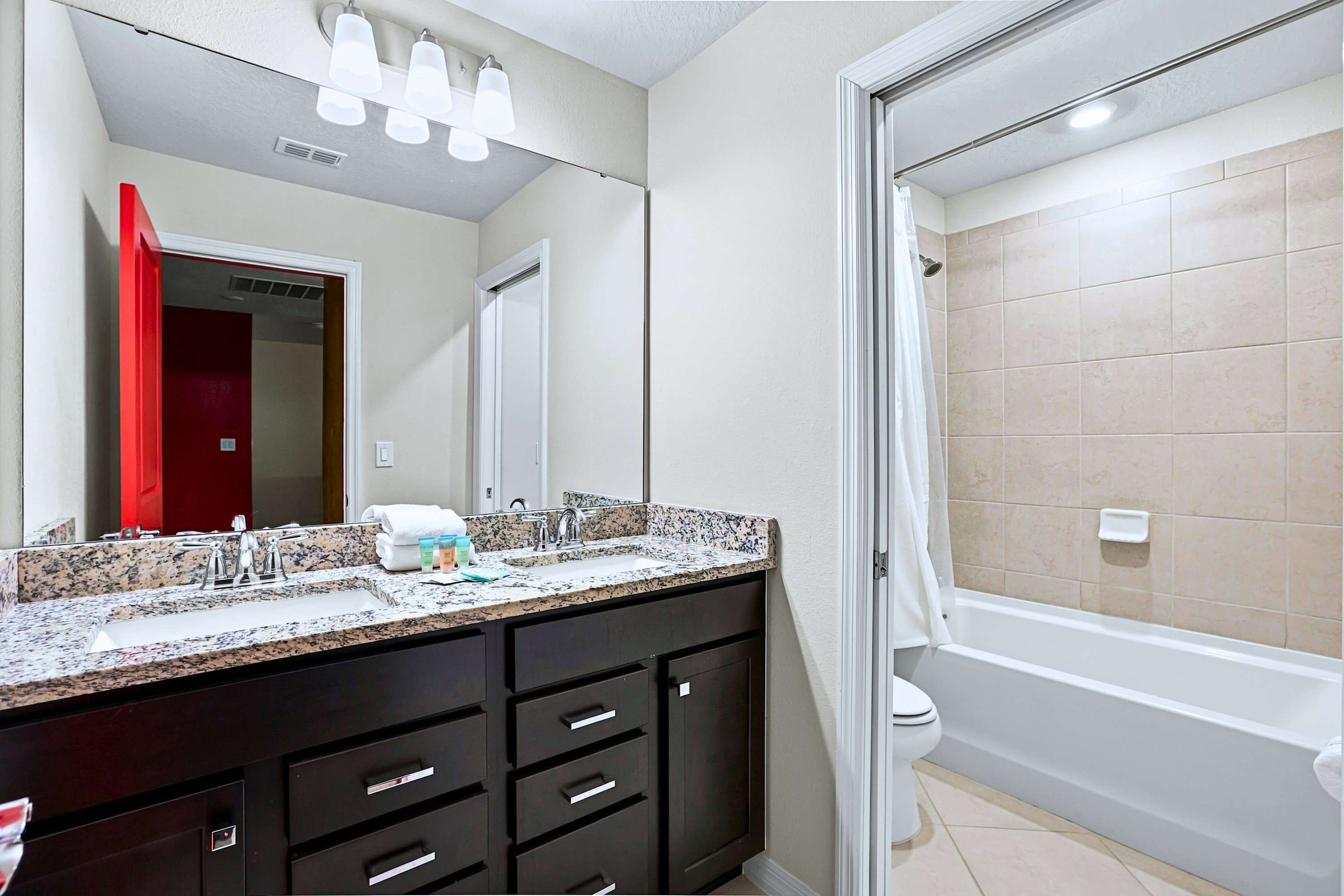 Enjoy the best of both worlds with a cozy bathtub-shower setup and beautiful vanity lighting.