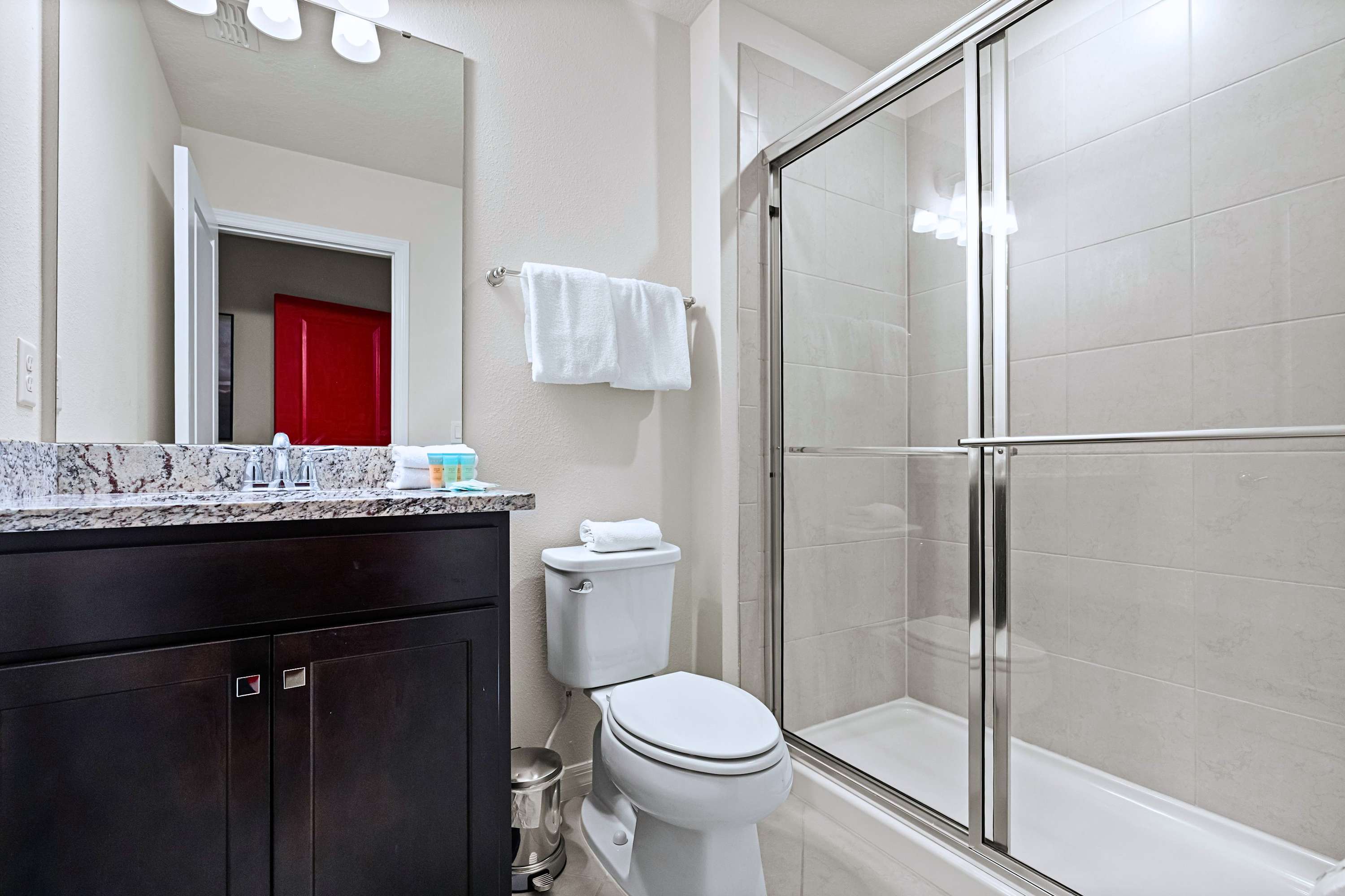 Everything you need to refresh: clean single vanity, large mirror, and a spacious walk-in shower.