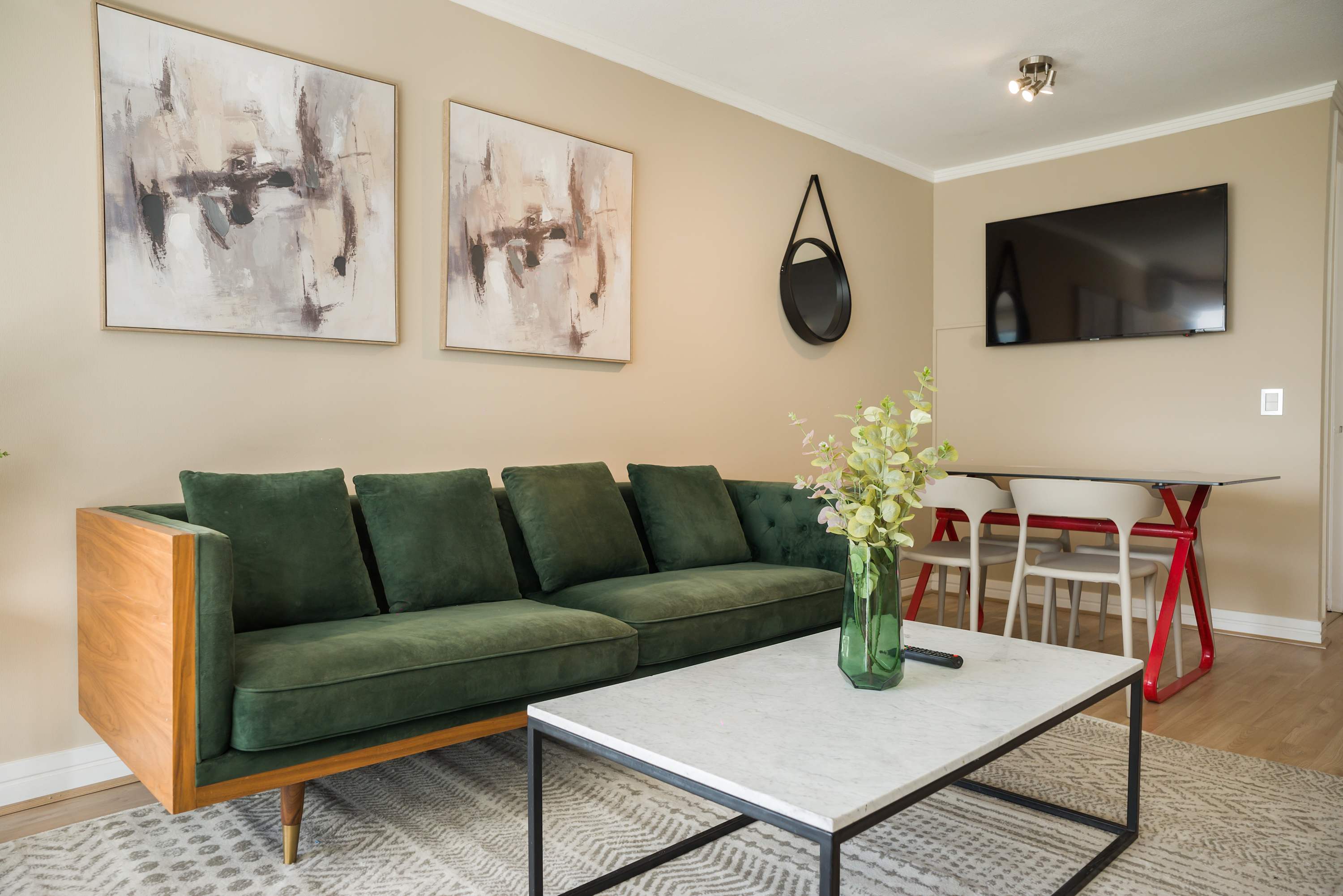 Contemporary living room with a deep green velvet sofa, marble-top coffee table, and stylish four-seat dining area.
