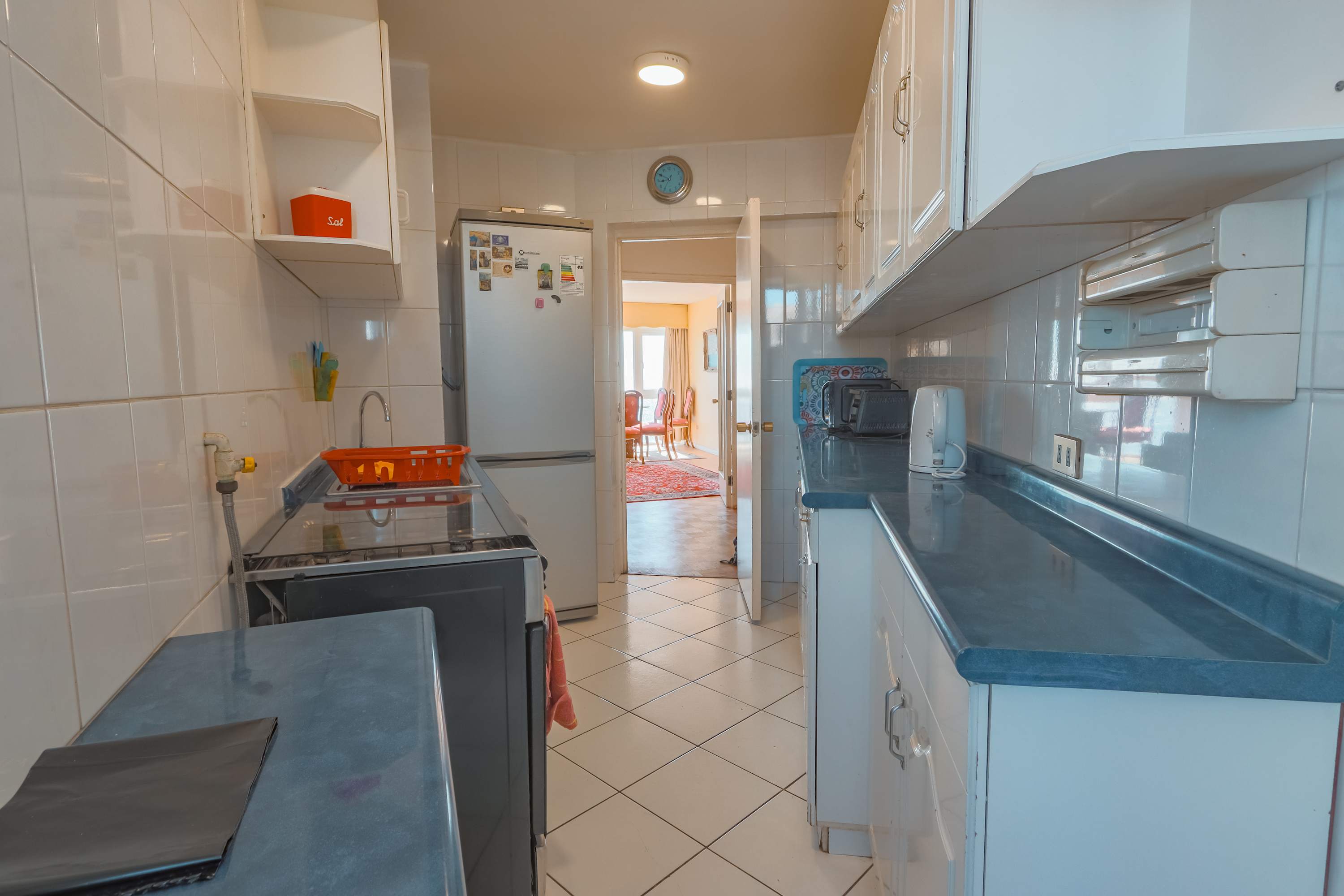 Private kitchen with full-size refrigerator, gas range, generous blue-gray counters, and direct access to the bright dining area.