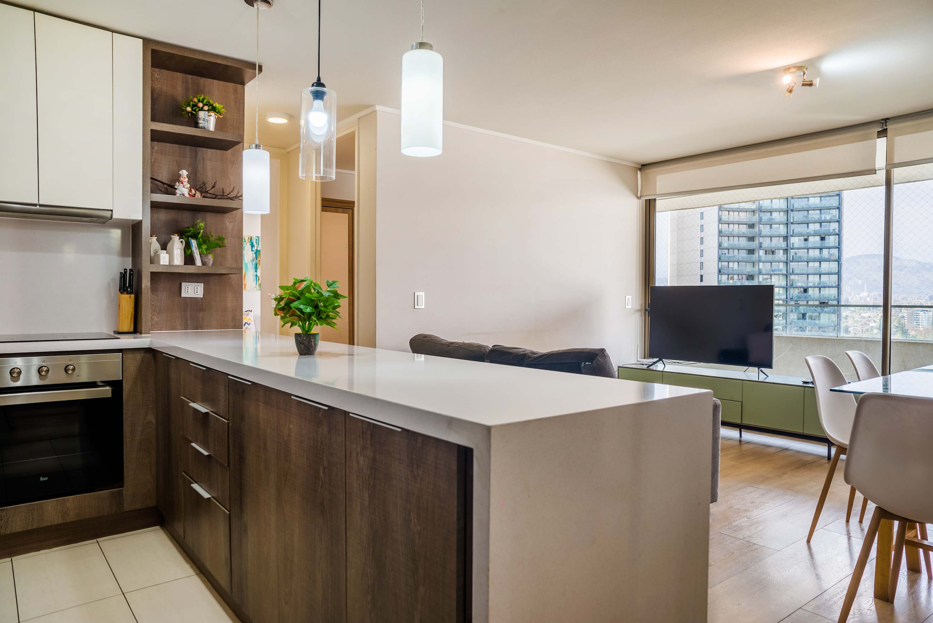 Modern open kitchen with a quartz peninsula, pendant lighting, and expansive windows overlooking the city and mountains.