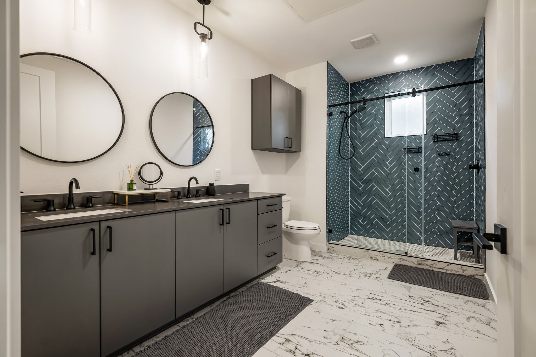 Bathroom with double vanity and herringbone tile shower