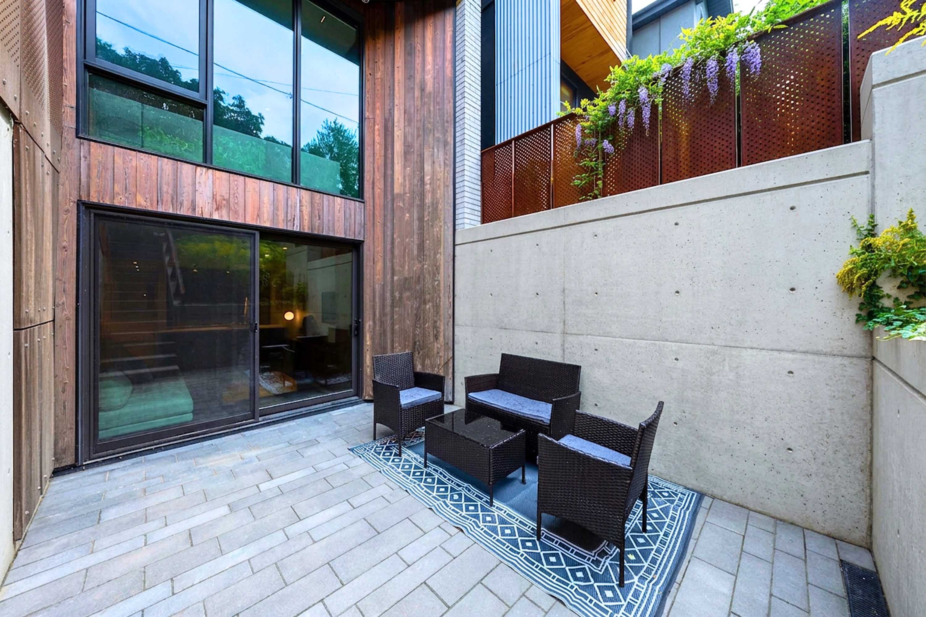 Private lower-level patio with comfortable outdoor seating and direct sliding-door access