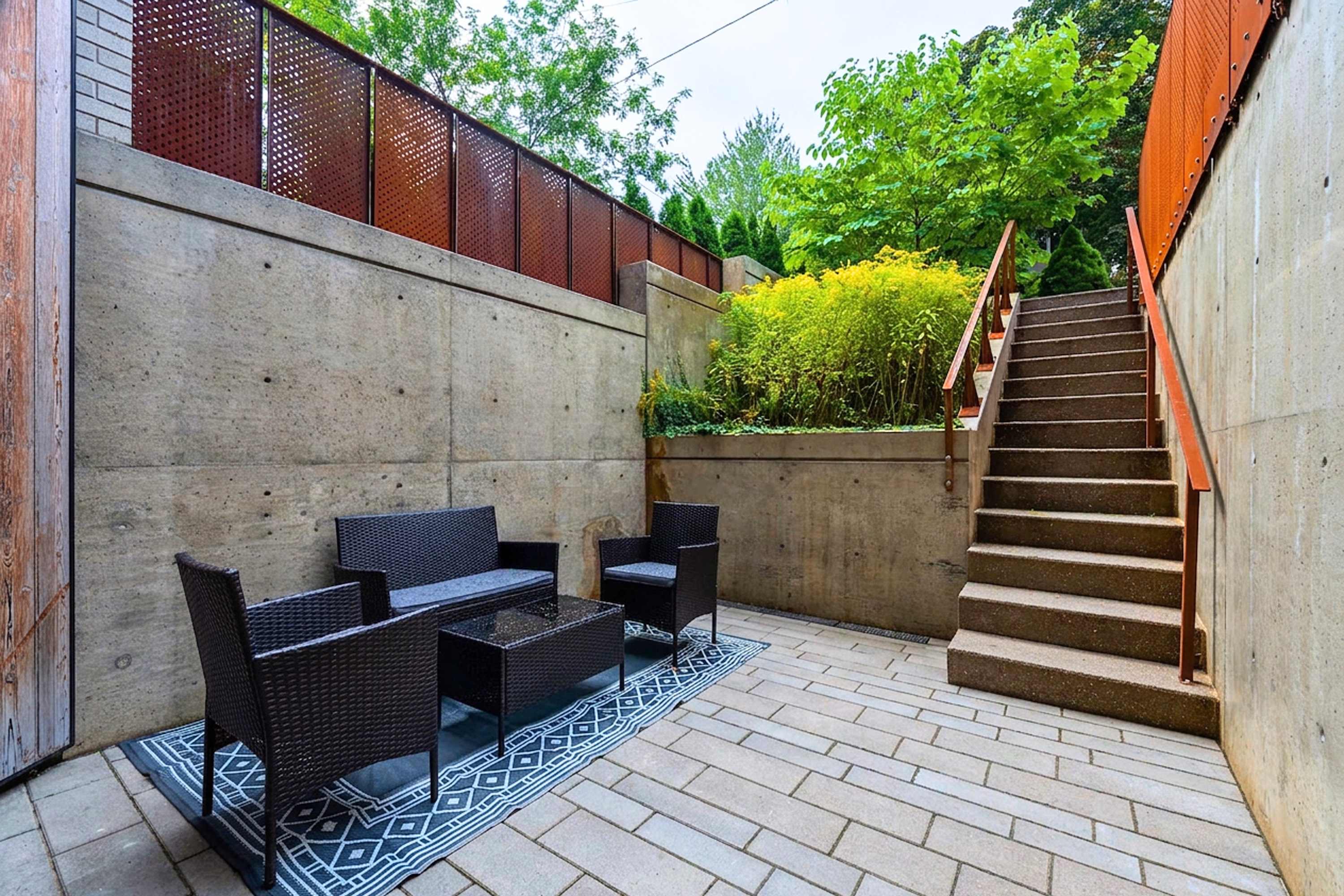 Sunken courtyard seating area featuring concrete privacy walls and lush greenery
