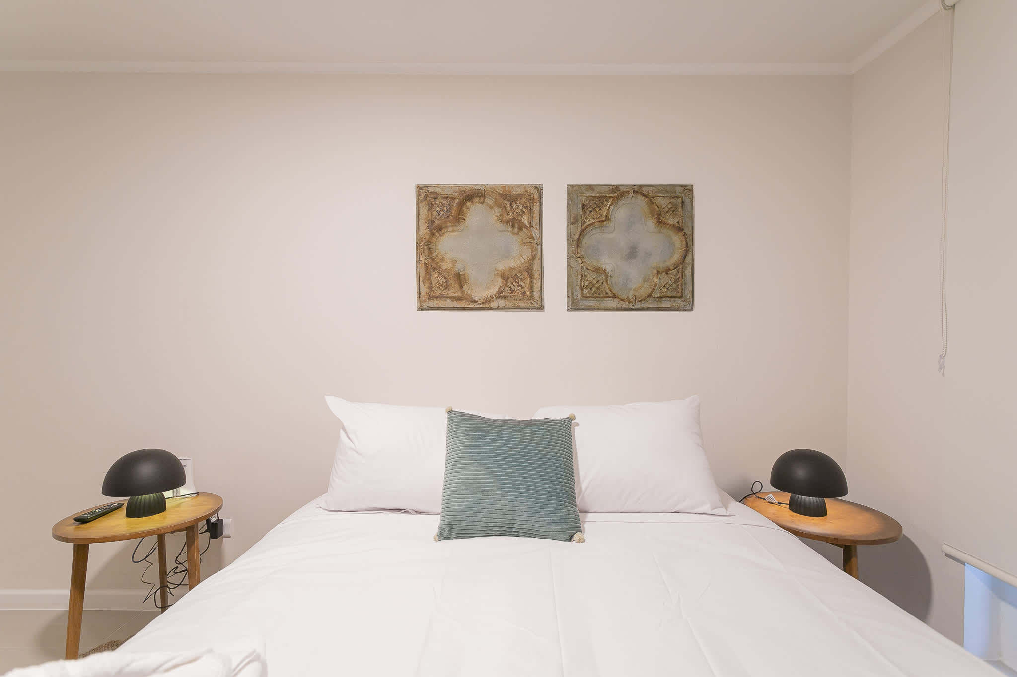 Private bedroom with crisp white bedding, matching wooden nightstands, dome lamps, and vintage-inspired wall panels.