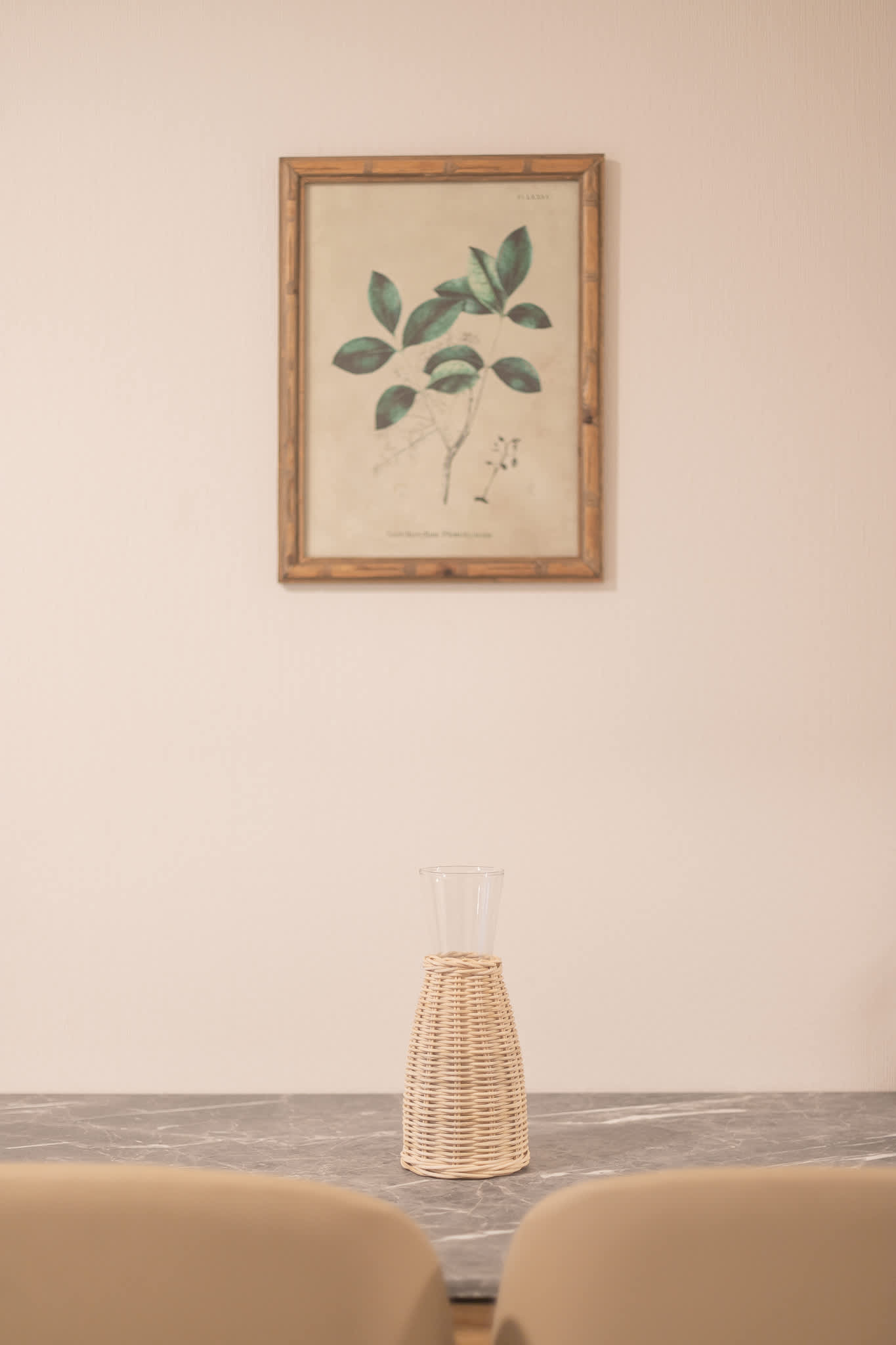 Intimate dining nook with two cream chairs, a marble-look table, and framed botanical artwork.