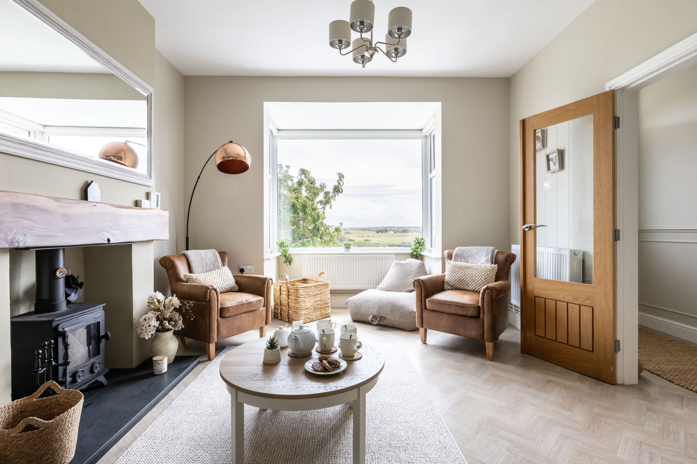 Wood-burning stove with wicker armchairs and French doors, pet-friendly cottage sleeping six in Bryn Du, Anglesey