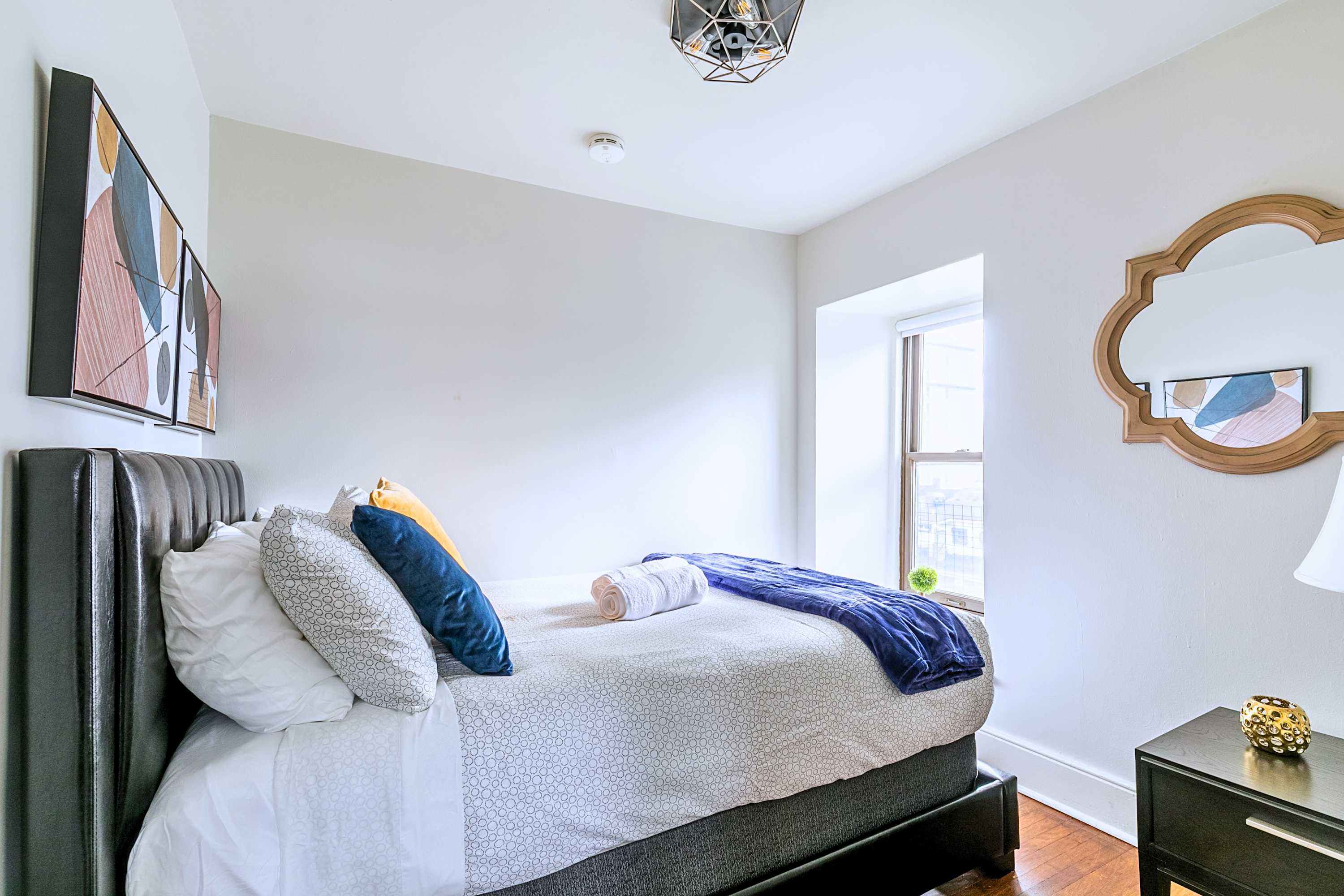 Restful bedroom featuring a plush tufted headboard, vibrant accent pillows, and sleek mirror