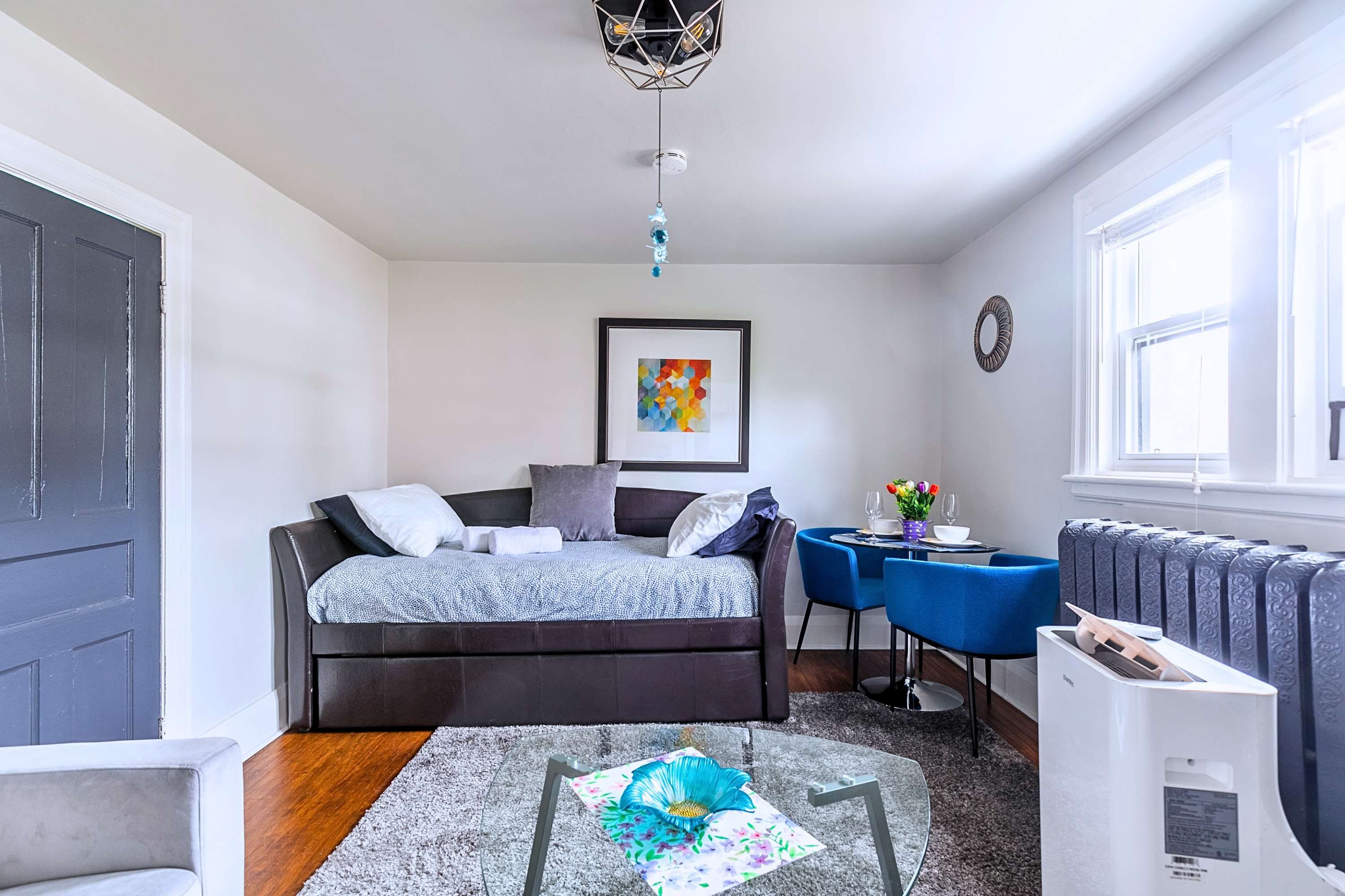 Sunlit room with a versatile daybed lounge, stylish glass coffee table, and blue dining chairs