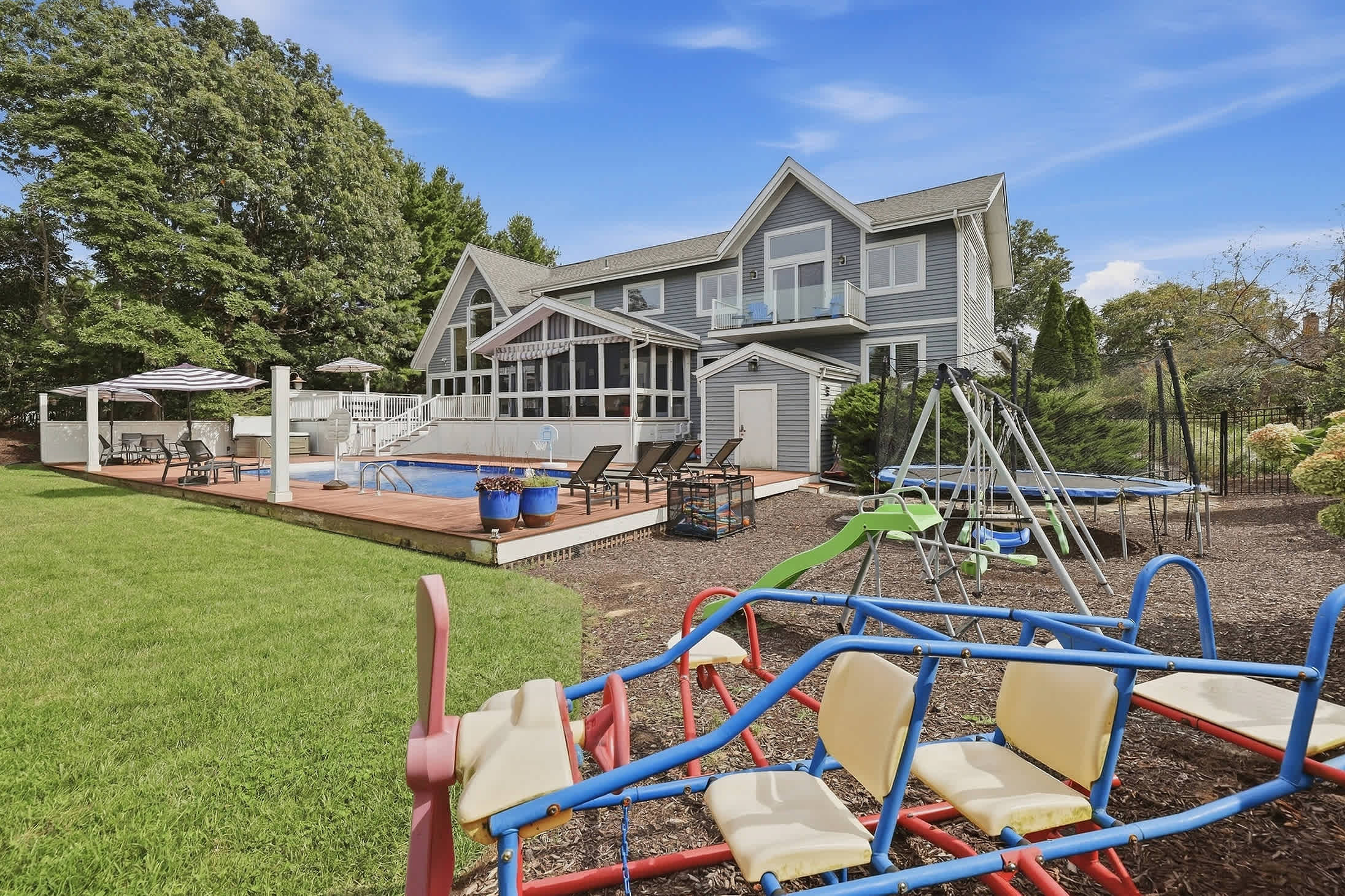 Backyard with pool, swing set, trampoline and room for outdoor play.