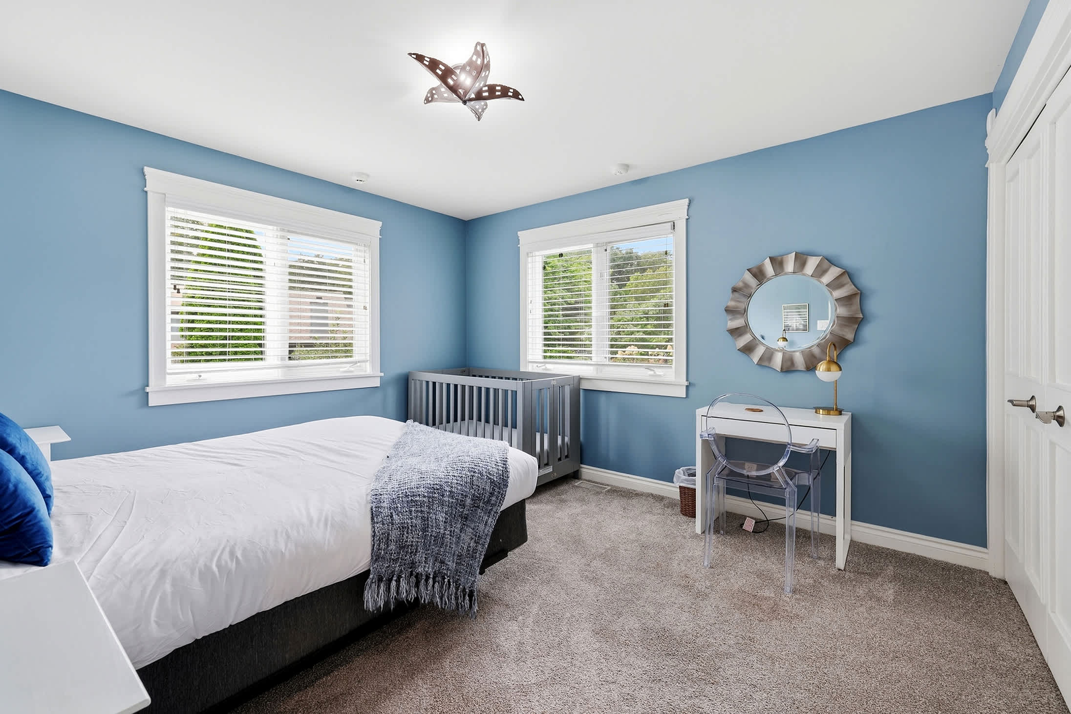 Guest room with bed, crib and workspace for families with little ones.