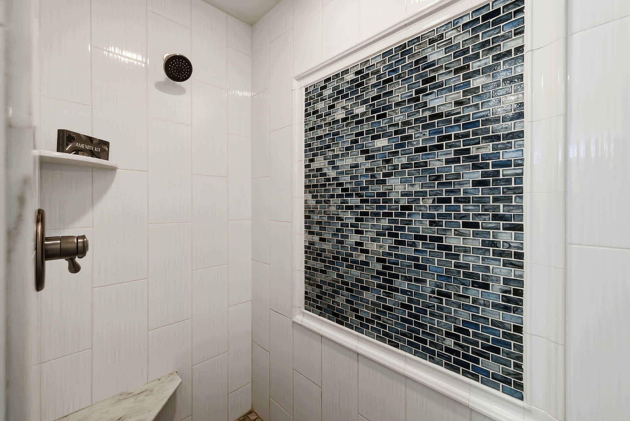 Walk in shower with built in bench and tiled accent wall.