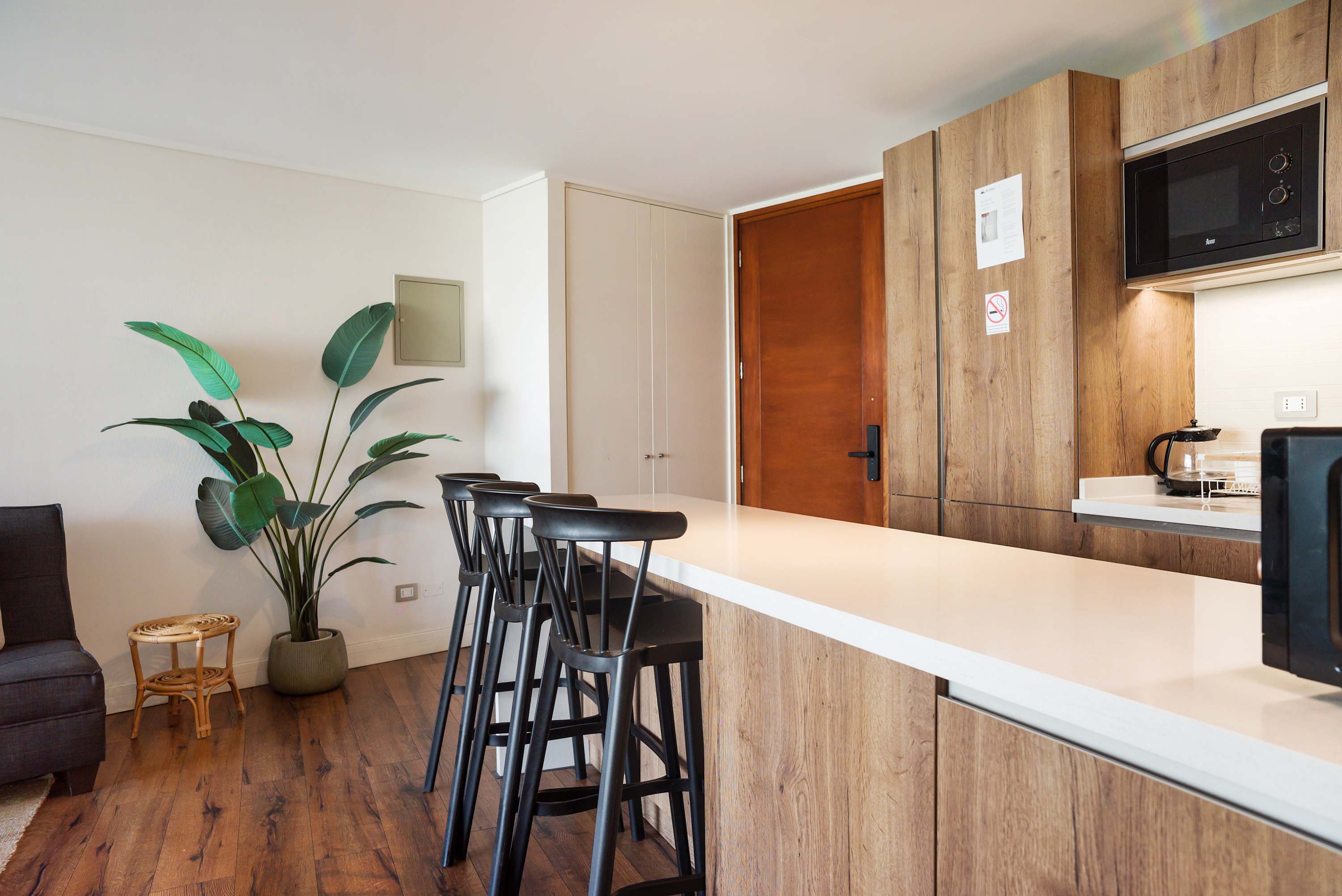 Modern private kitchen with a spacious white island, seating for guests, wood cabinetry, and a built-in microwave.