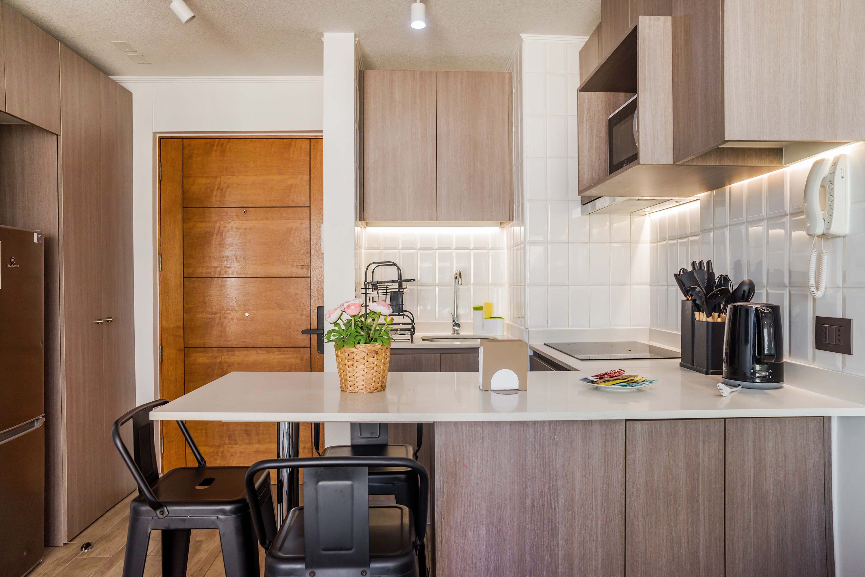 Private kitchen with wood cabinetry, a bright tiled backsplash, induction cooktop, and peninsula dining area for relaxed meals.