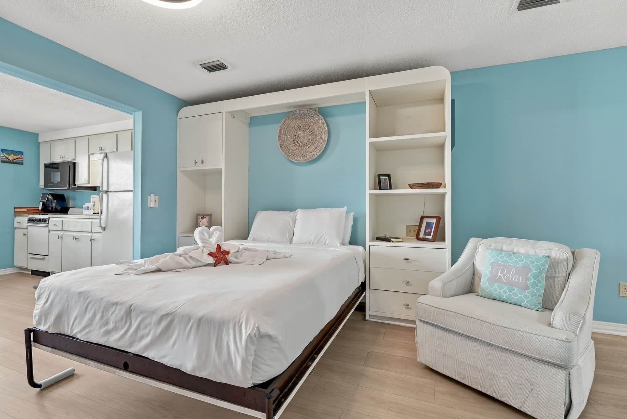 St Thomas SQ 1209C – Studio bedroom featuring a pull-down bed, kitchenette, and white armchair with a "Relax" pillow.