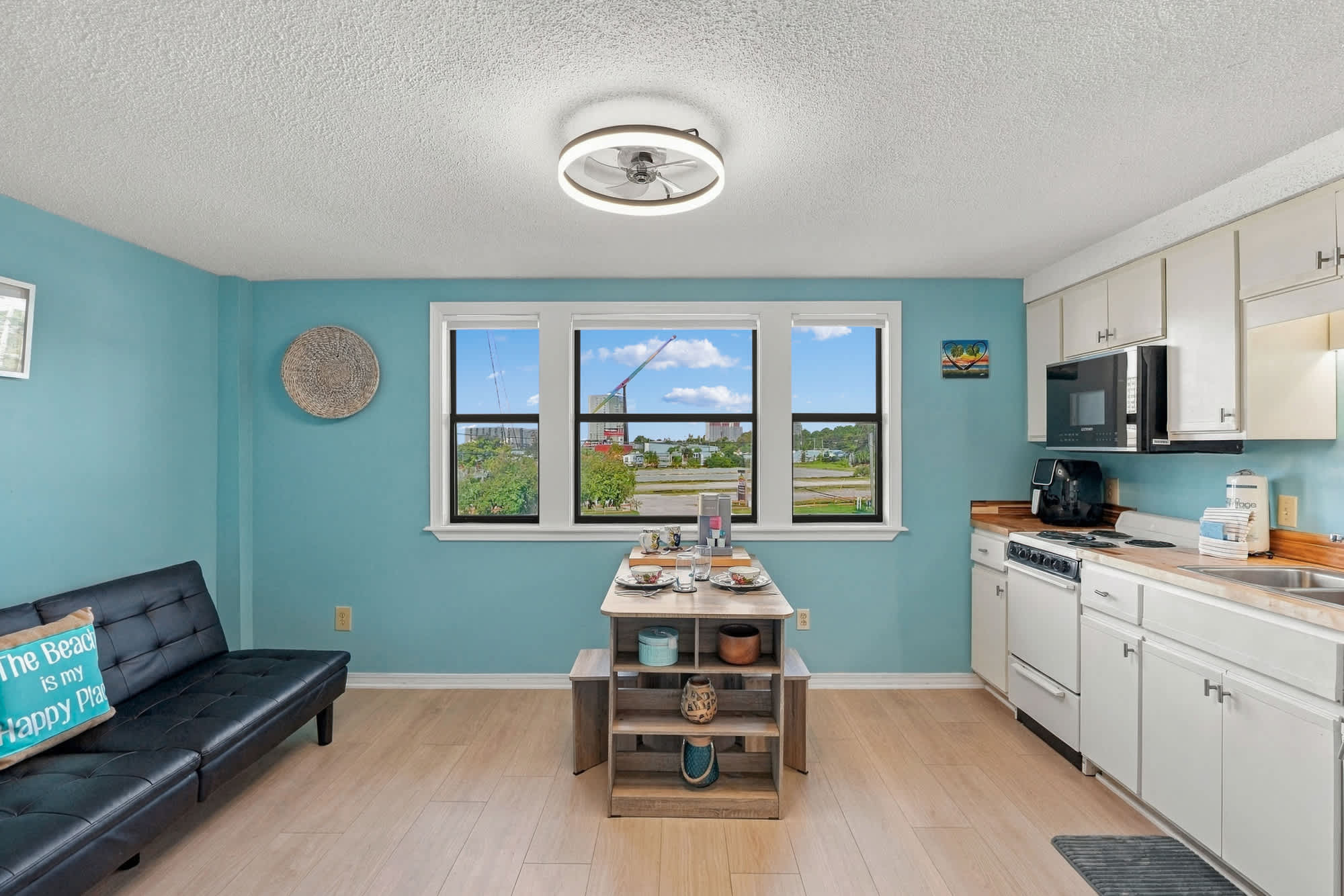 St Thomas SQ 1209C – Bright kitchen and living area with large windows, table set for dining, and a view of the outdoors.