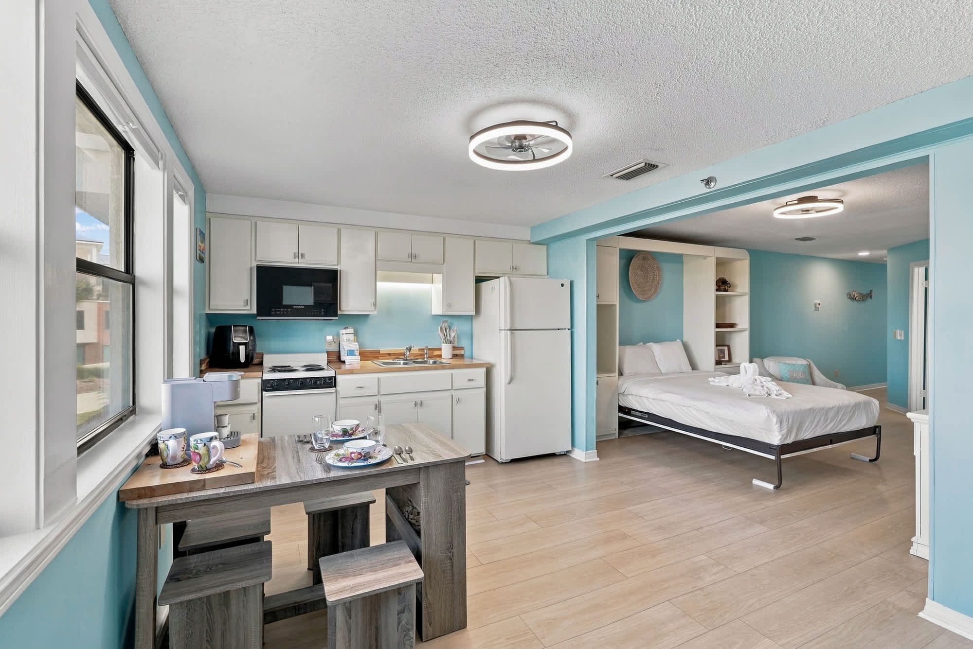 St Thomas SQ 1209C – Studio rental with kitchen area, dining table, and bed in a light blue room.