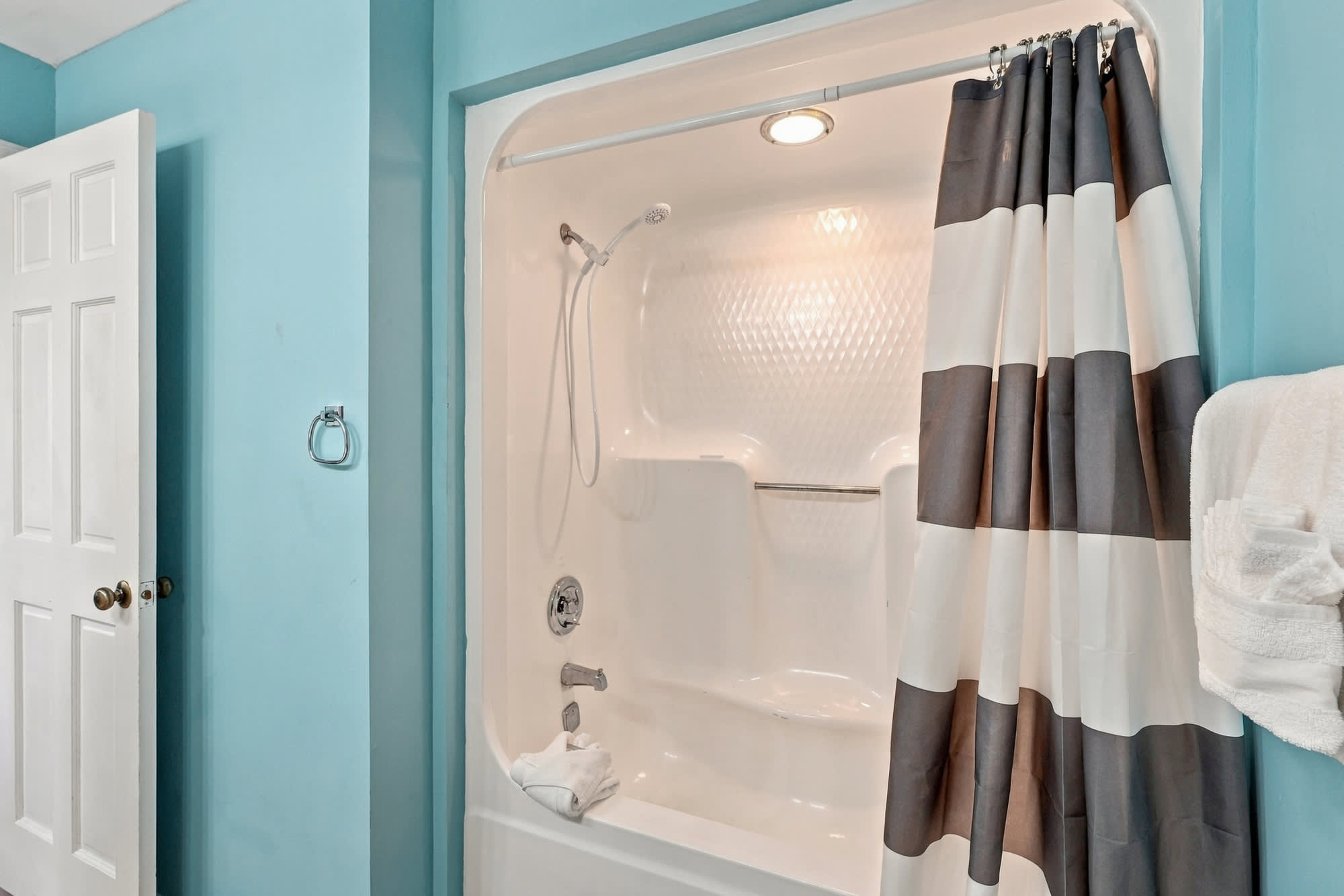 St Thomas SQ 1209C – Bathroom with a shower-tub combo, blue walls, and striped shower curtain.