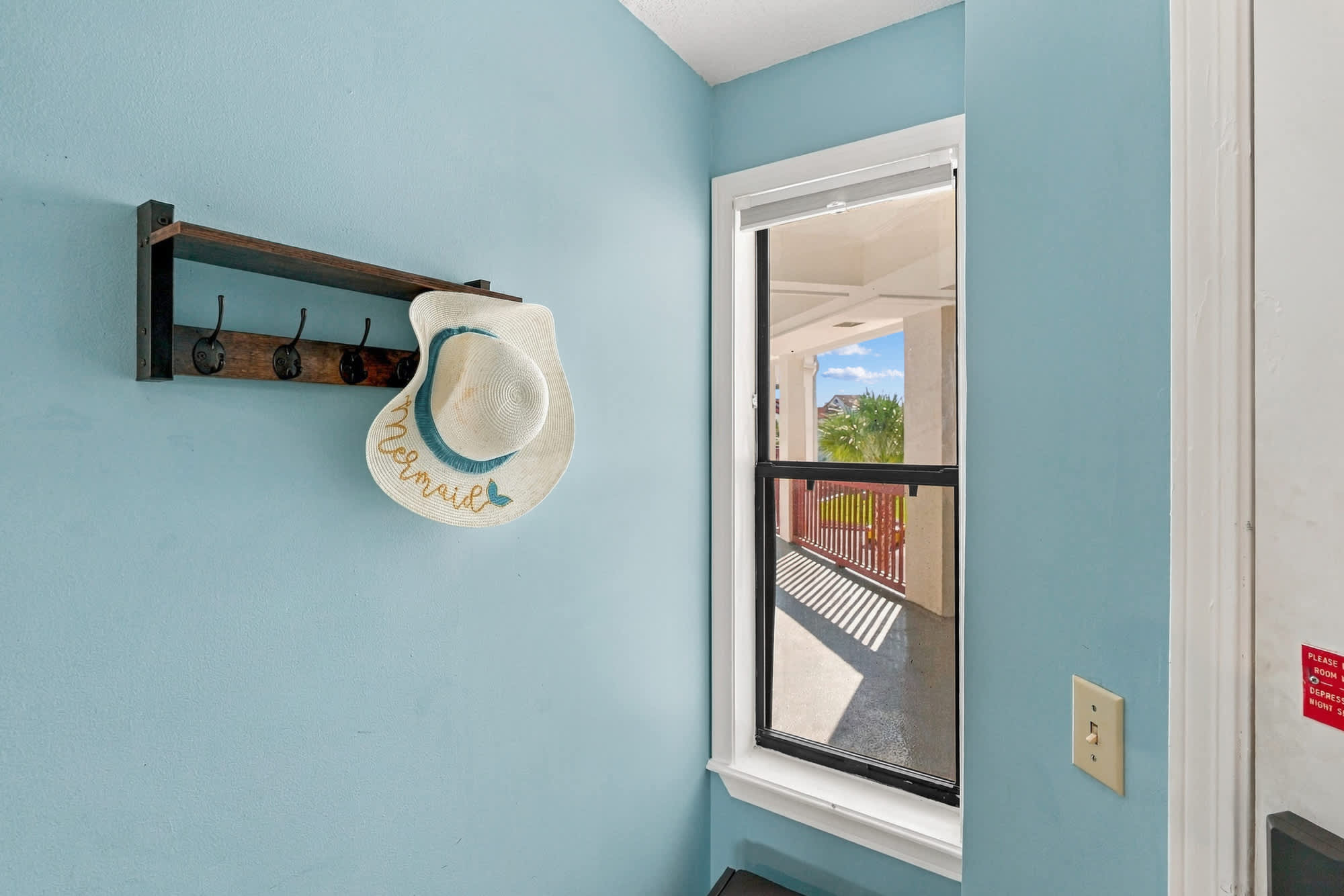 St Thomas SQ 1209C – Entryway with blue walls, wall-mounted hat rack, and a view of a patio through a window.