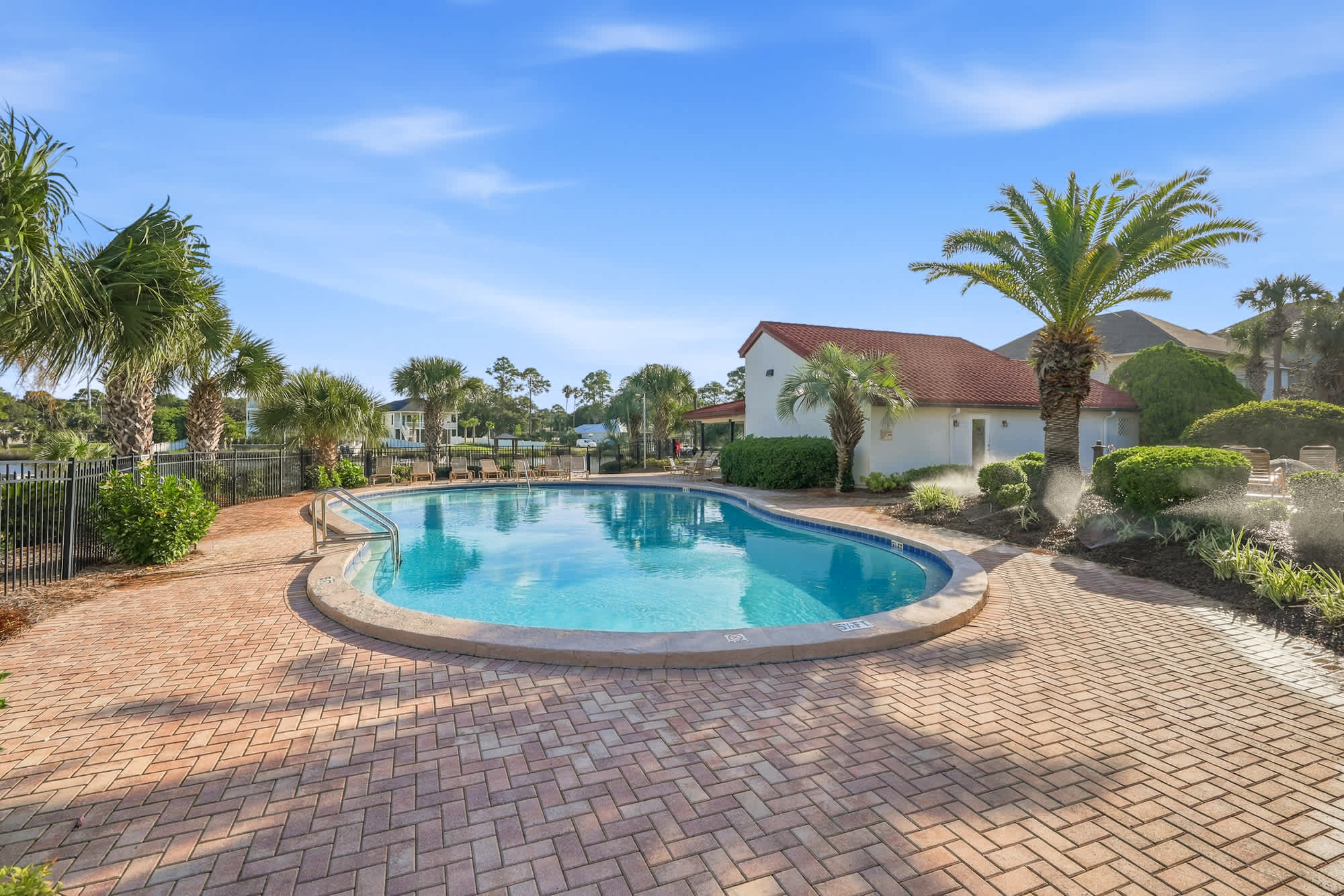 St Thomas SQ 1209C – Pool area with curved, blue water, surrounded by palm trees and a small building in the background.
