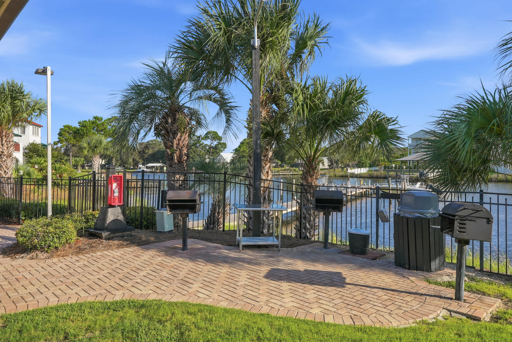 St Thomas SQ 1209C – Outdoor grilling area with palm trees and waterfront view, featuring multiple grills and picnic table.