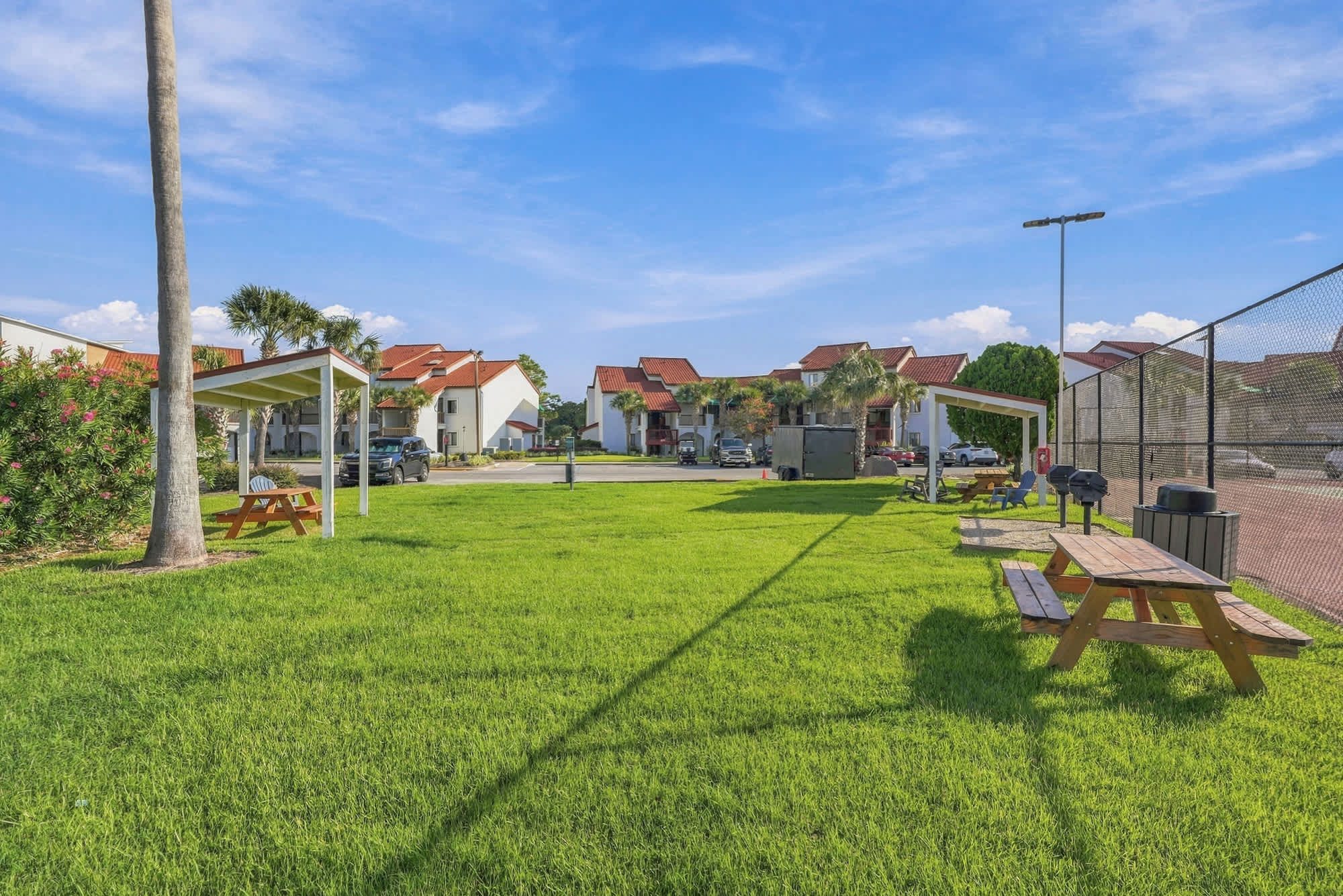 St Thomas SQ 1209C – Lawn area with picnic tables, palm trees, and nearby residential buildings in the background.
