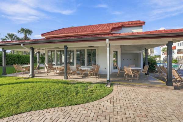 St Thomas SQ 1302B – Outdoor patio with tables and chairs, surrounded by greenery and leading to a pool area.