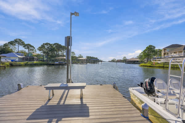 St Thomas SQ 1302B – Dock overlooking a calm waterway with boat and surrounding trees and homes.