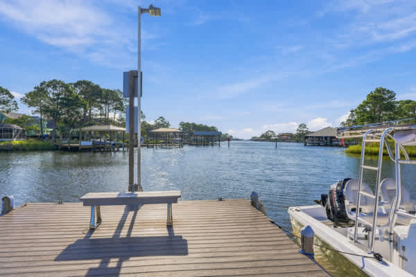 St Thomas SQ 1302B – Dock view overlooking a calm waterway, with boat and surrounding trees and homes.