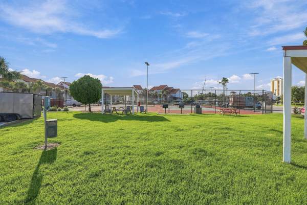 St Thomas SQ 1302B – Lush green lawn with tennis courts and shaded seating areas in the background.