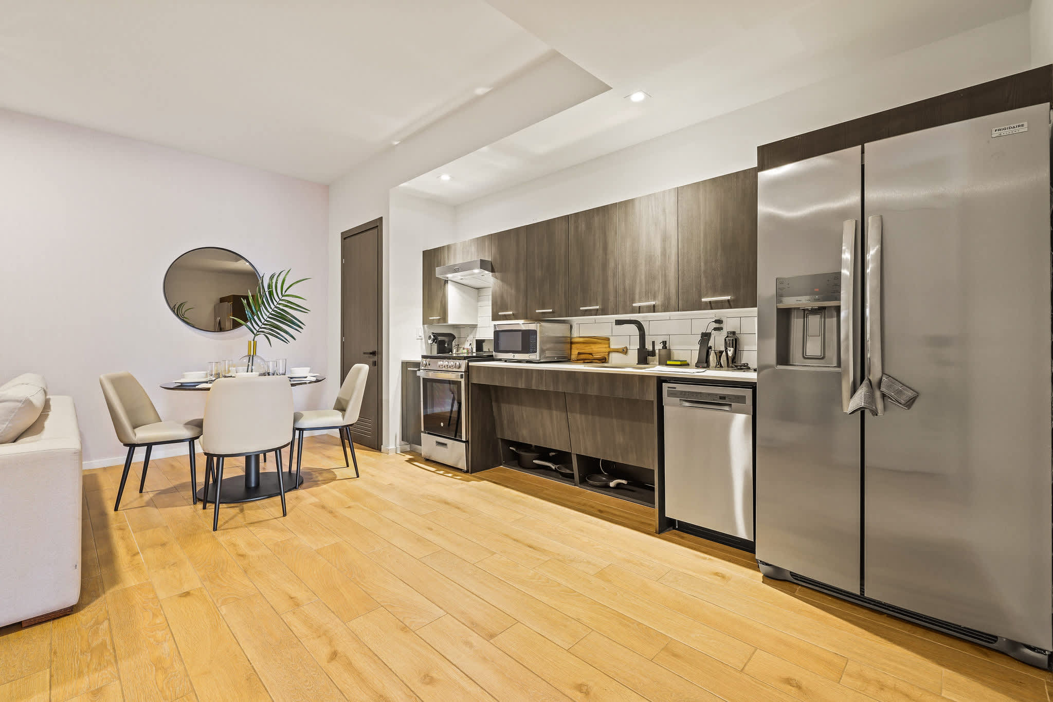 Modern studio kitchen with dark wood cabinetry, stainless-steel appliances, and a set dining nook for easy meals at home.