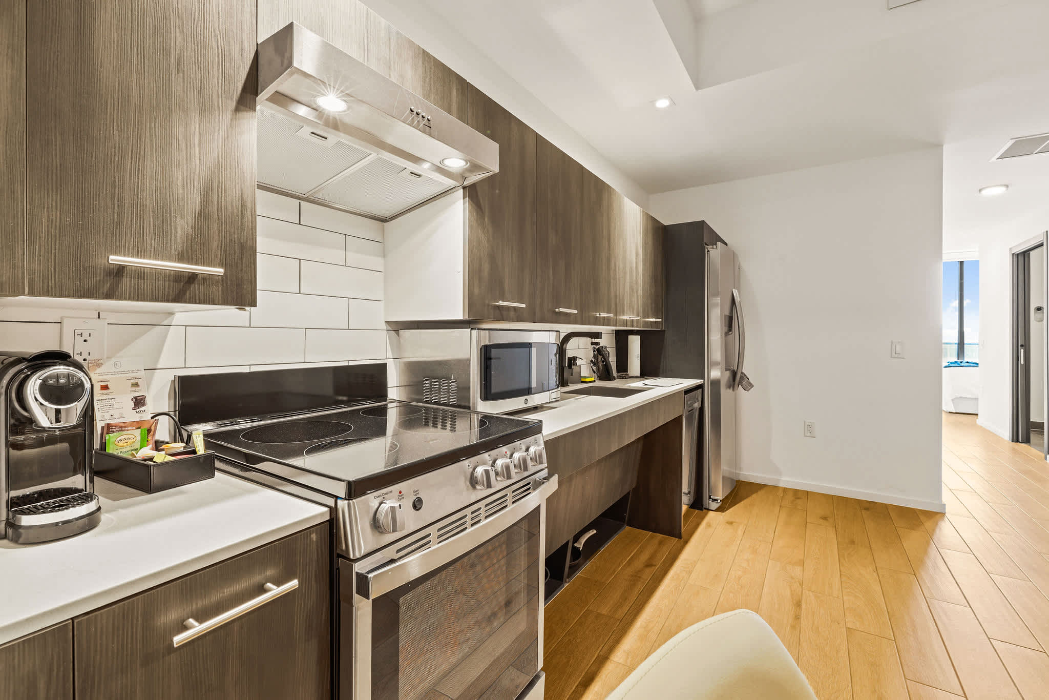 Private kitchen with dark wood cabinetry, stainless-steel appliances, and a bright white subway-tile backsplash.