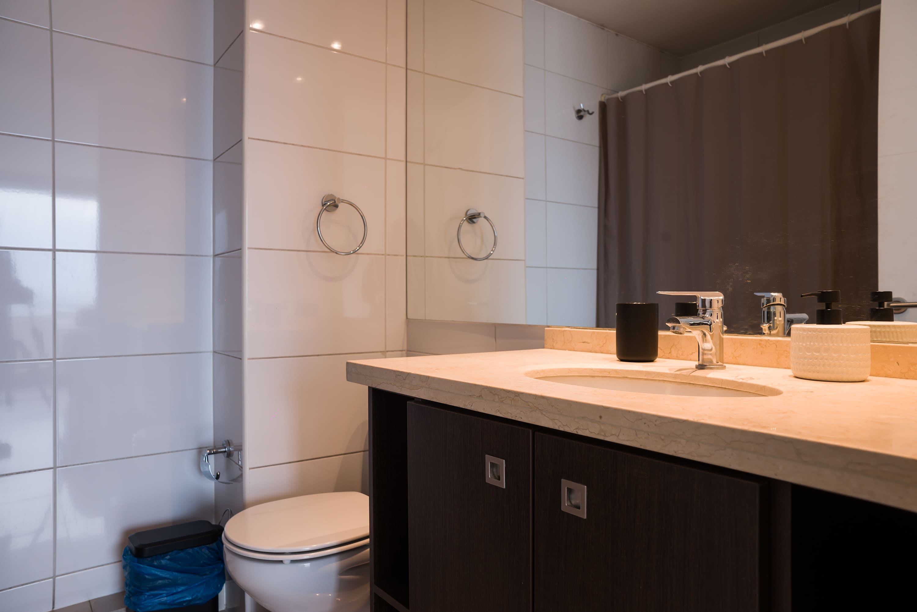 Private bathroom with a marble-look vanity, chrome faucet, mirrored storage, and a dark shower curtain.