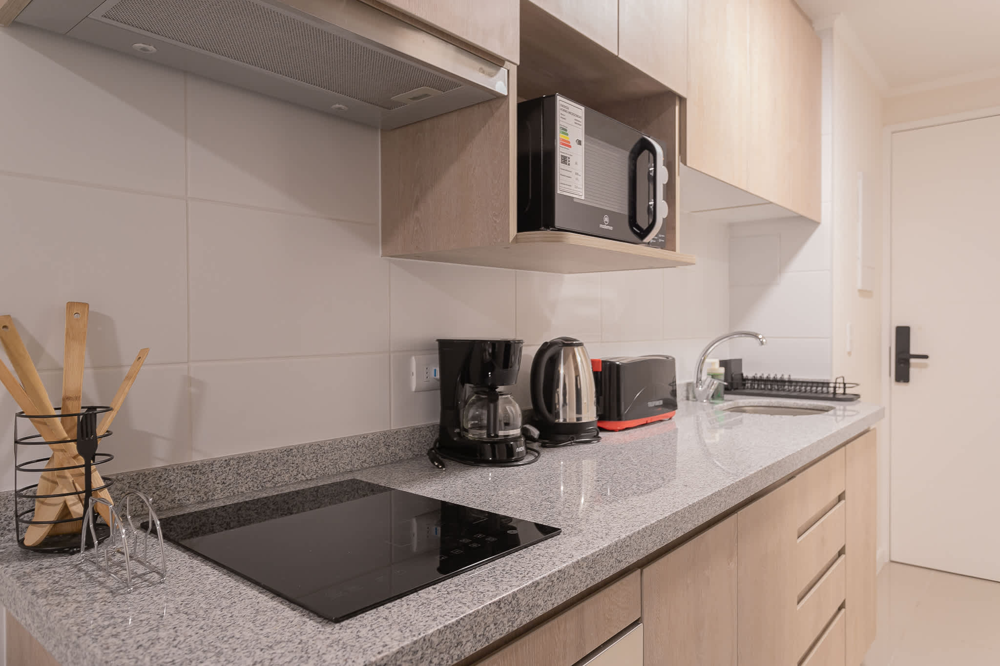 Private kitchen with a granite worktop, induction cooktop, microwave, coffee maker, kettle, and toaster for convenient studio stays.