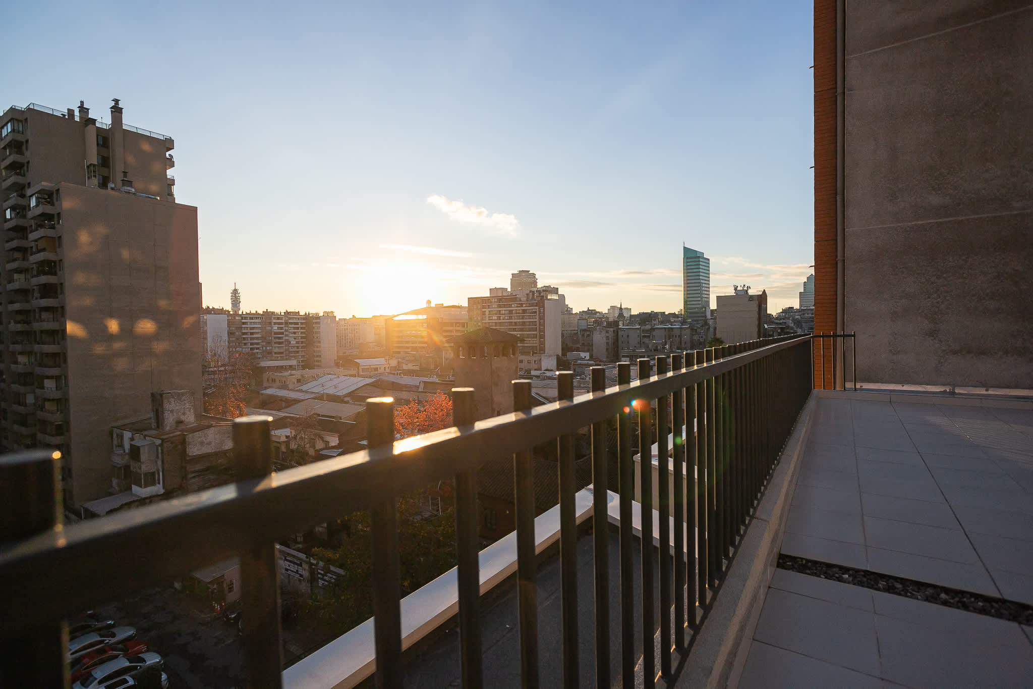Private balcony with a sweeping city skyline and golden sunset views over Santiago.