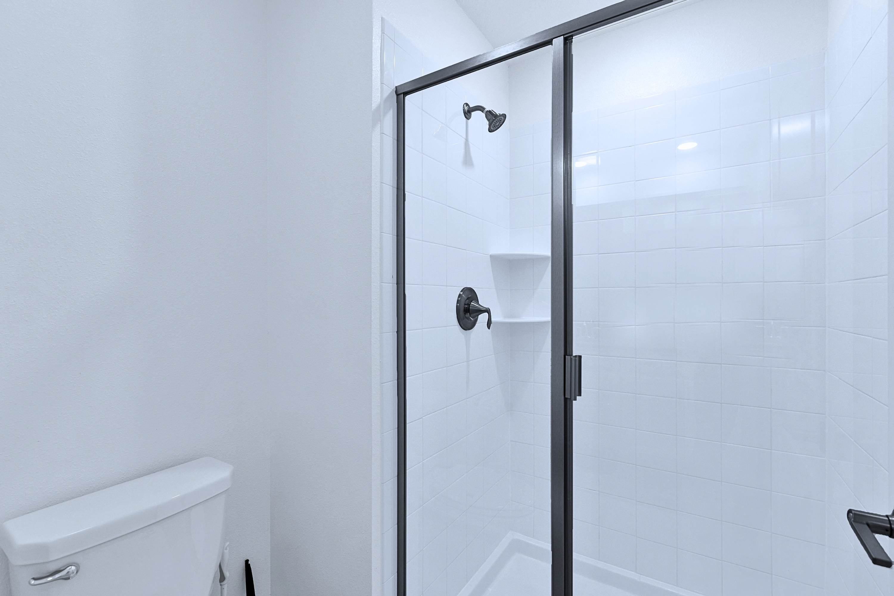 Full bathroom featuring a modern tiled walk-in shower, fresh towels, and toilet.